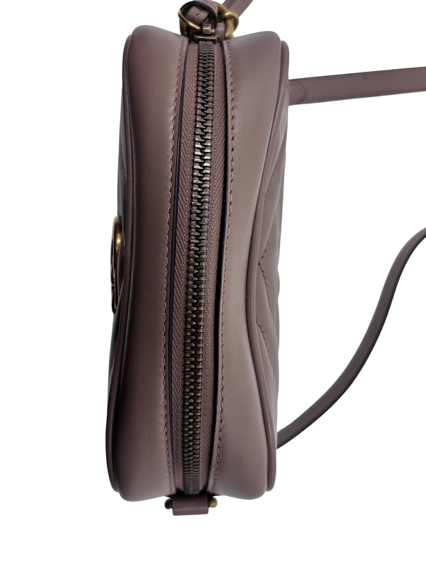 Side profile of a small beige Posh Purse Co. Gucci camera bag featuring a secure zip-top closure and shoulder strap.