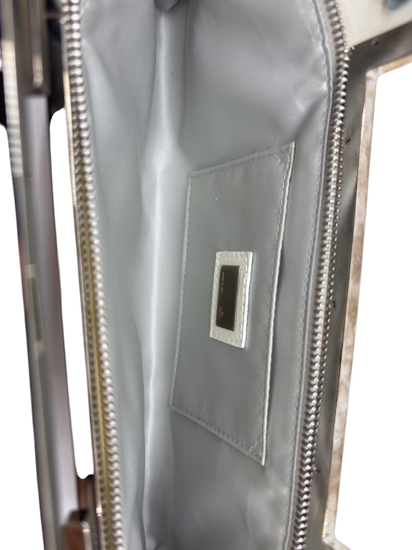 Interior of a white Posh Purse Co. Fendi Crossword clutch with silver lining and a branded leather patch.