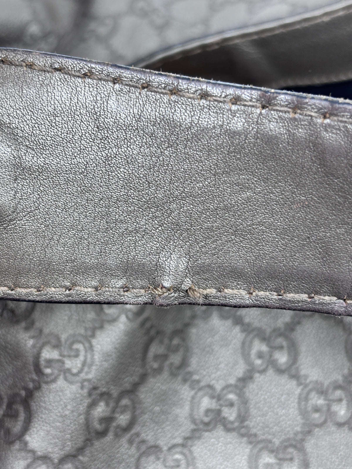 Close-up of Posh Purse Co. pre-owned gray Gucci Jockey shoulder bag showing leather strap texture and stitching detail.