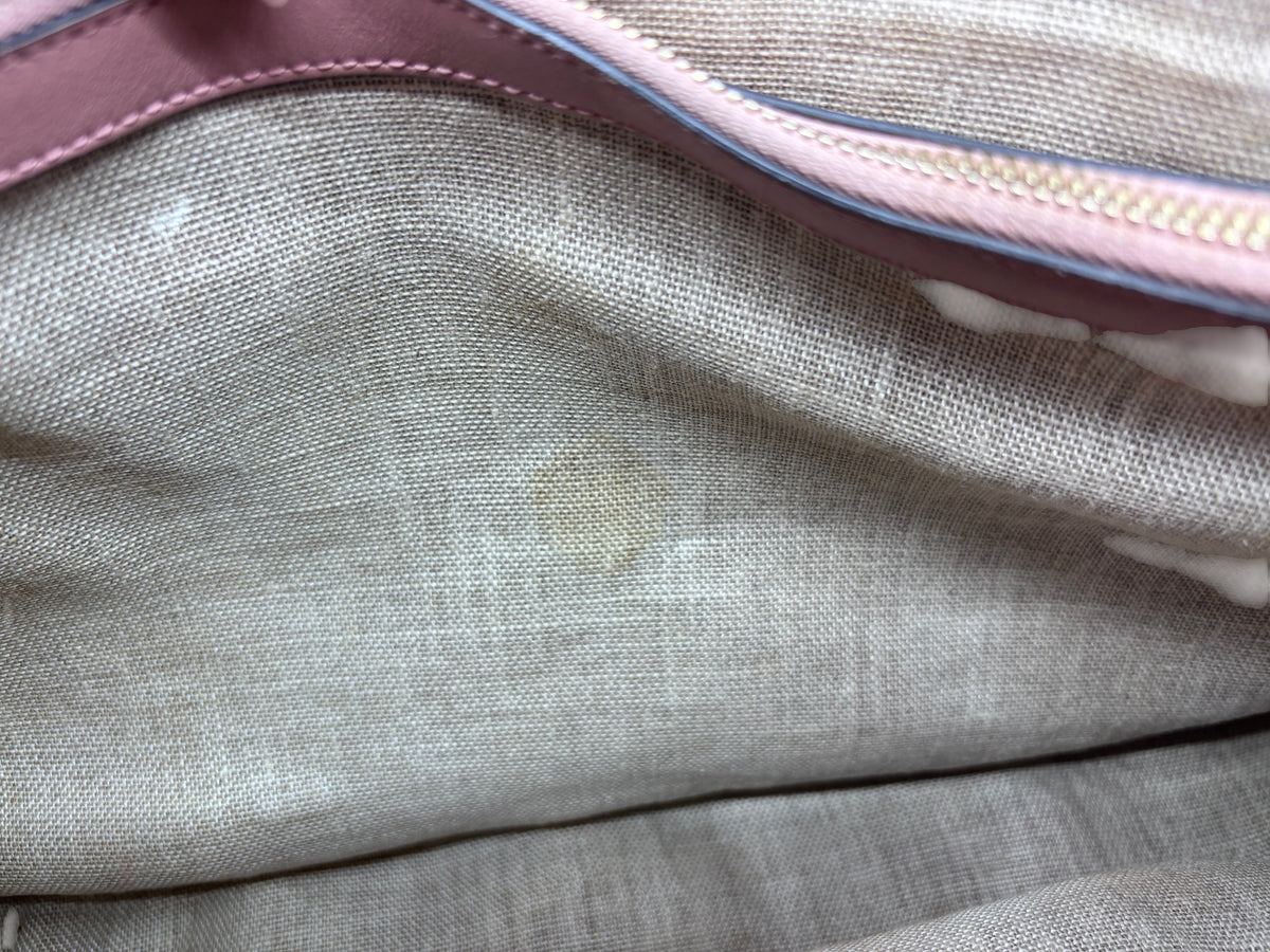 Interior view of a Posh Purse Co preloved pink Gucci handbag showing the fabric lining with a small stain