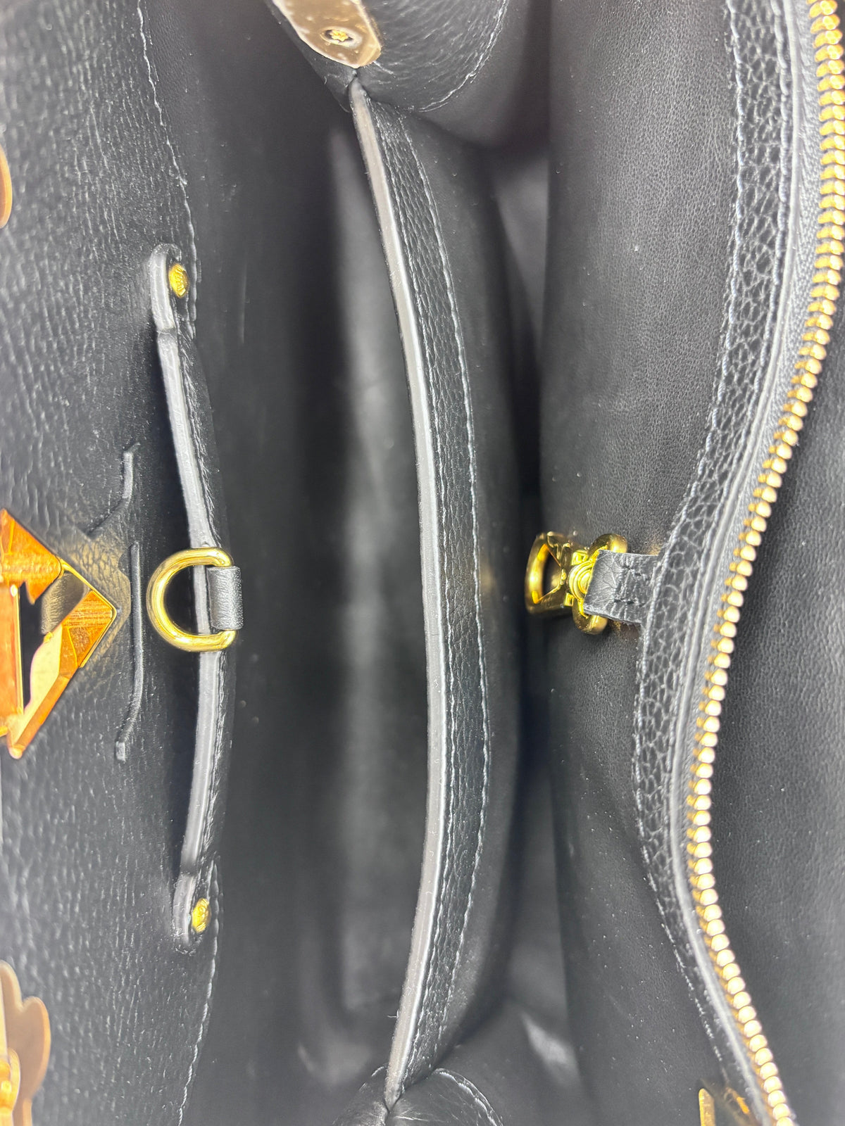 Interior view of a black Posh Purse Co Louis Vuitton Capucines MM handbag showing leather lining and gold hardware.