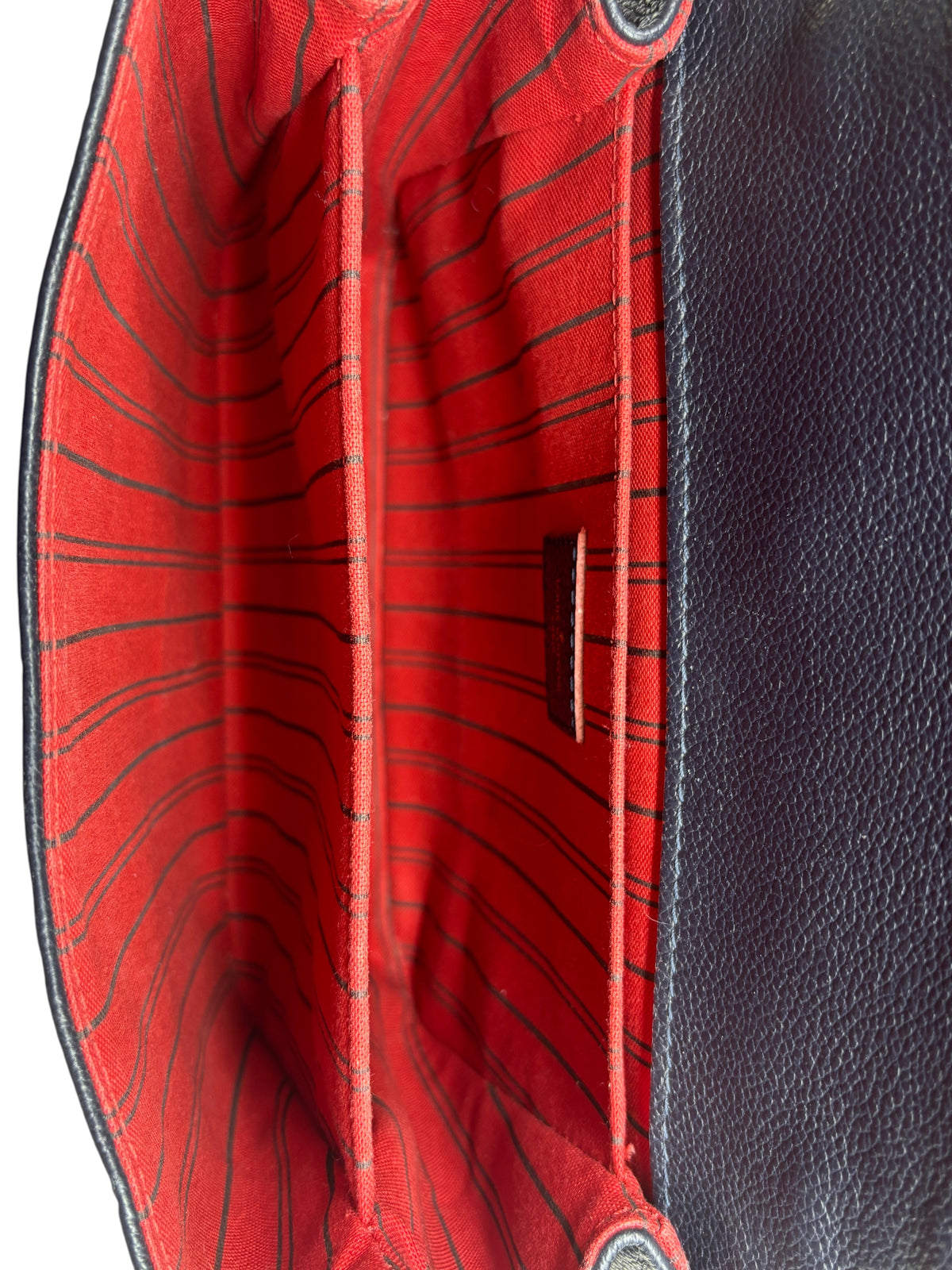 Interior of Posh Purse Co. Louis Vuitton Pochette Metis bag featuring red striped textile lining and three compartments.