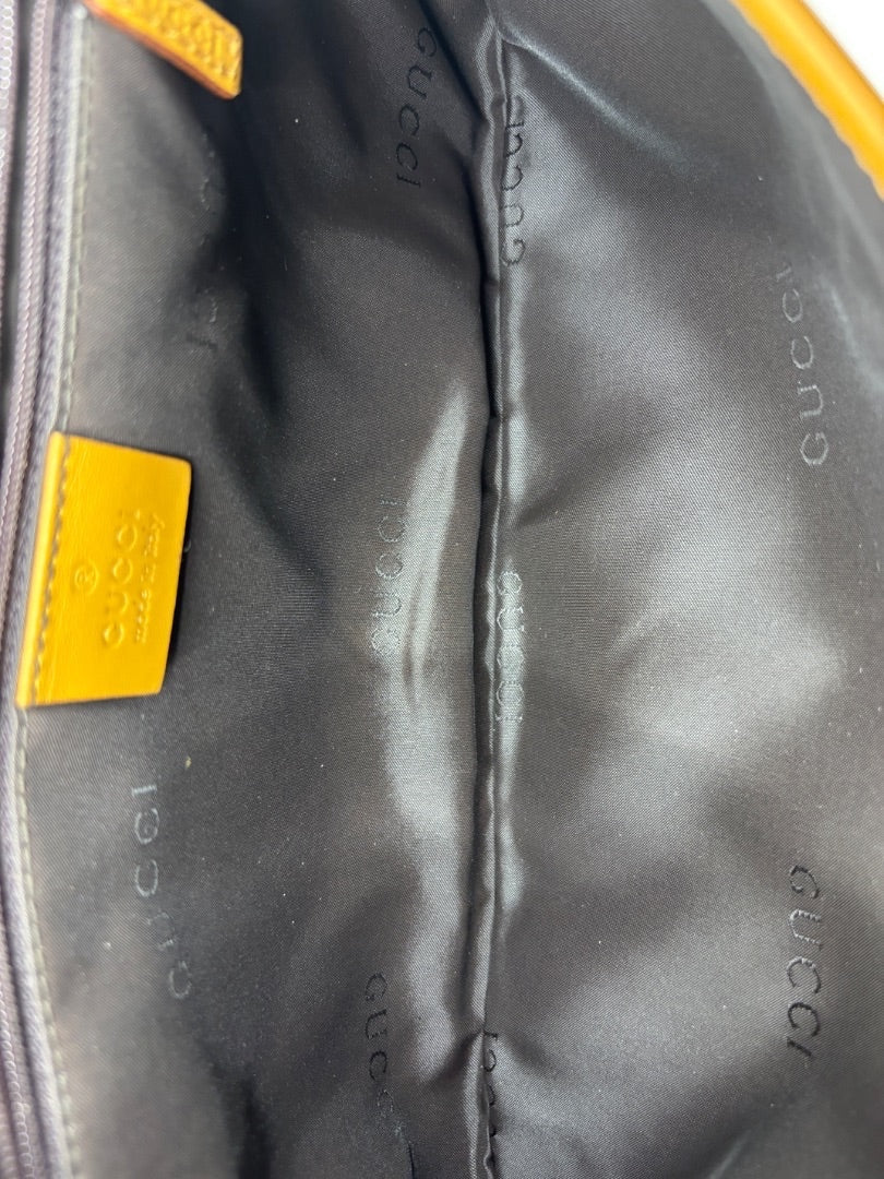 Interior of Posh Purse Co. vintage Gucci shoulder bag with black logo fabric lining and yellow leather brand tag.