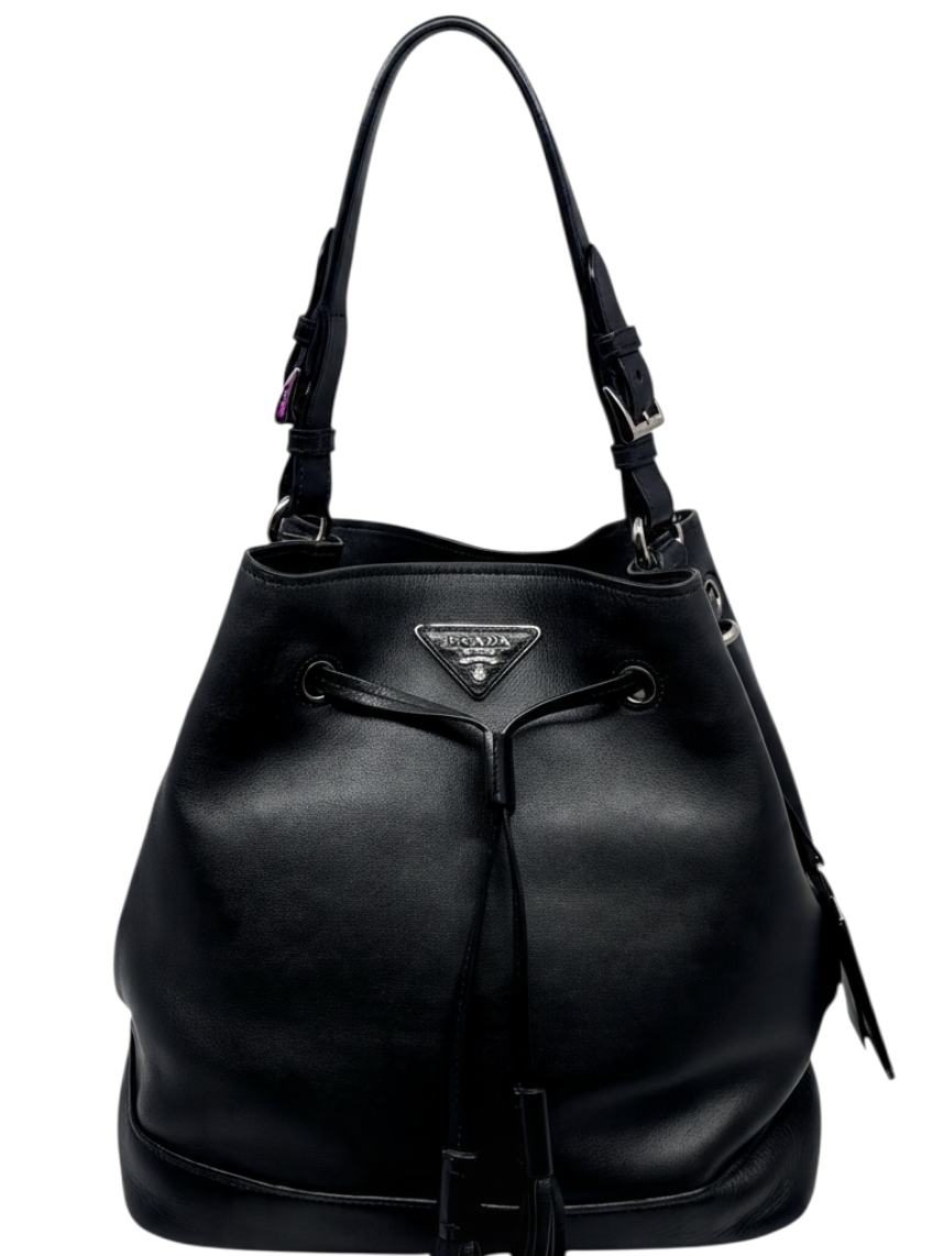 Posh Purse Co. black leather Prada bucket bag with drawstring closure and iconic triangle logo on a white background