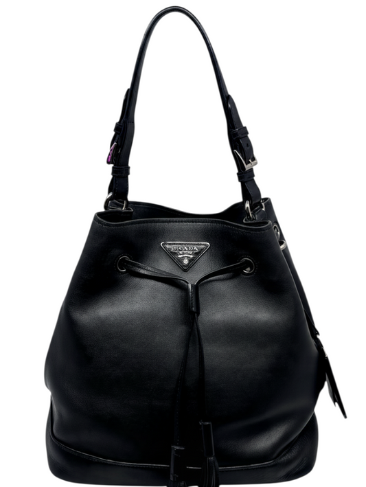 Posh Purse Co. black leather Prada bucket bag with drawstring closure and iconic triangle logo on a white background