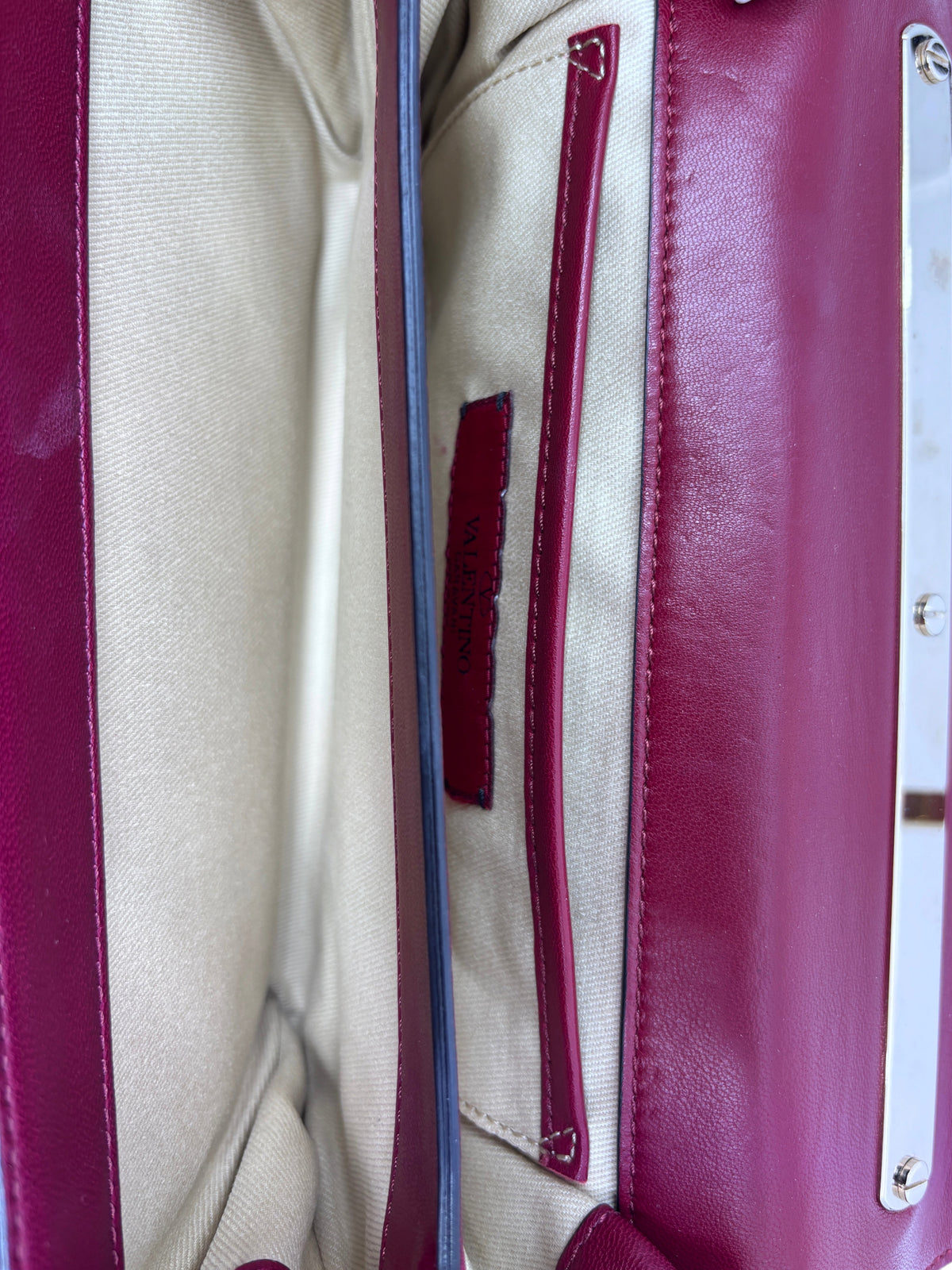 Interior view of a Posh Purse Co. preloved red Valentino flower crossbody bag showing the fabric lining and logo tag