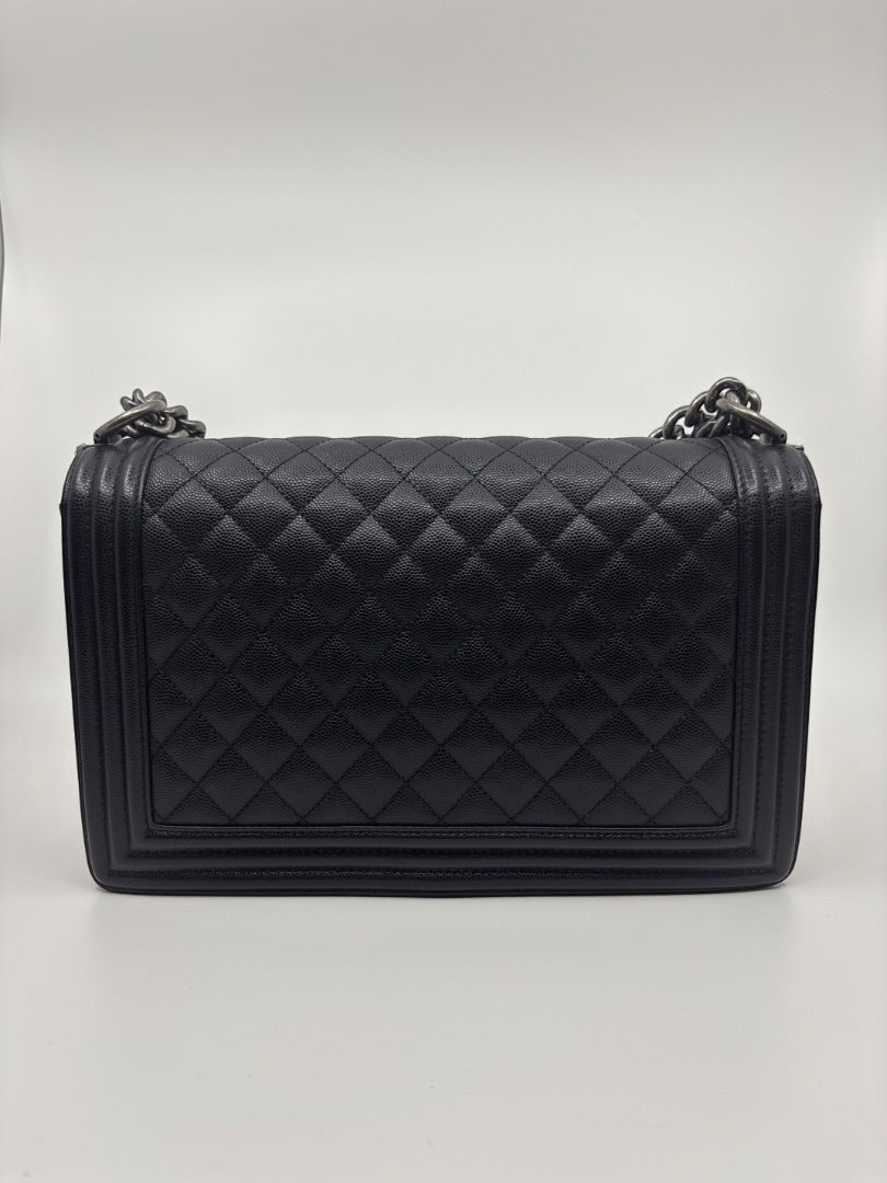 Posh Purse Co. large black Chanel Boy Bag in caviar leather with quilted diamond pattern and chain strap.