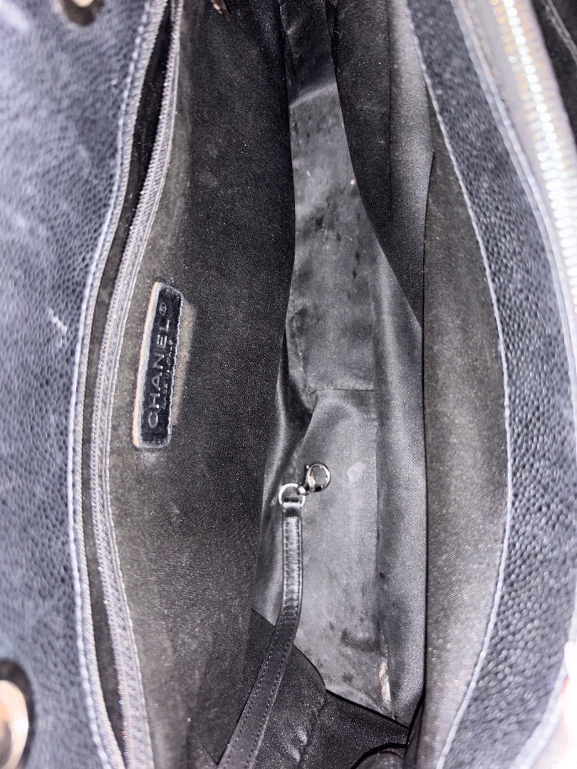 Interior of a black Chanel Grand Shopping Tote made of caviar leather with silver-tone hardware and multiple compartments.