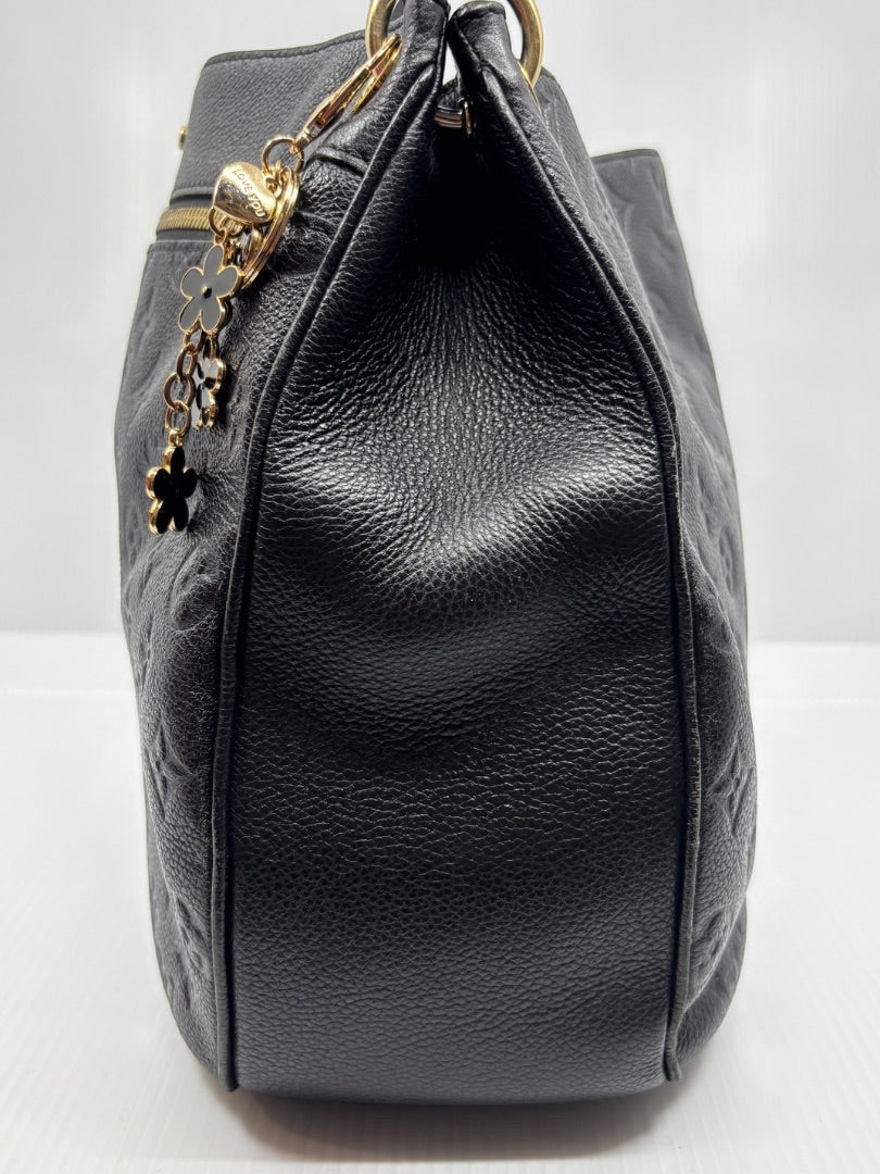 Side view of black Louis Vuitton Monogram Empreinte Spontini bag with gold charm from Posh Purse Co.