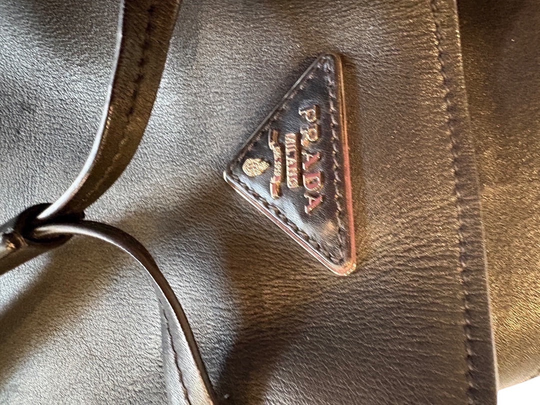 Posh Purse Co. black Prada leather bucket bag with iconic triangular logo and shoulder strap.
