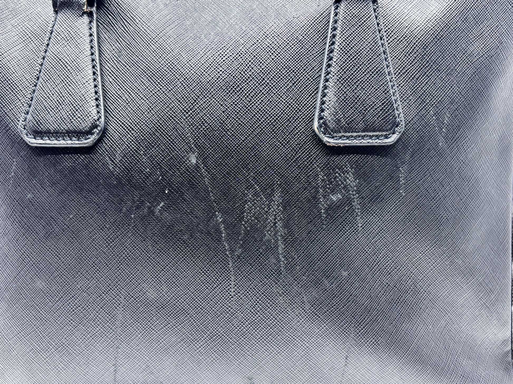 Posh Purse Co black Prada Saffiano leather briefcase showing surface wear and marks on the textured exterior