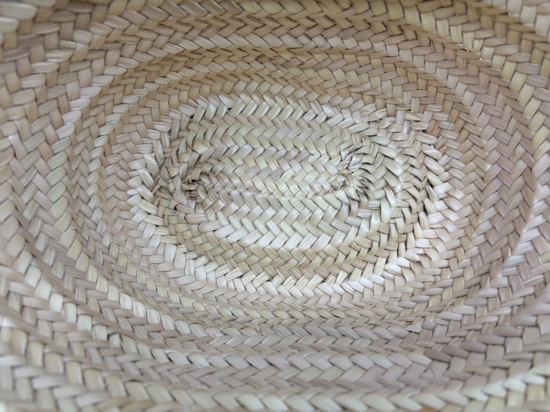 Interior base of a Posh Purse Co. Celine Classic Panier bag featuring natural woven raffia in a tight basket pattern.