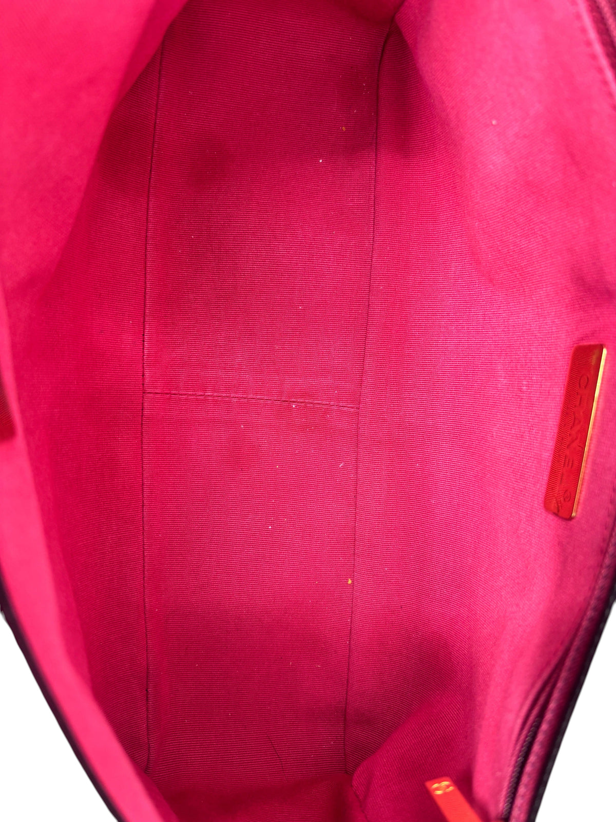 Interior view of a preloved Posh Purse Co Chanel 19 Flap bag featuring a vibrant pink fabric lining and gold logo tag