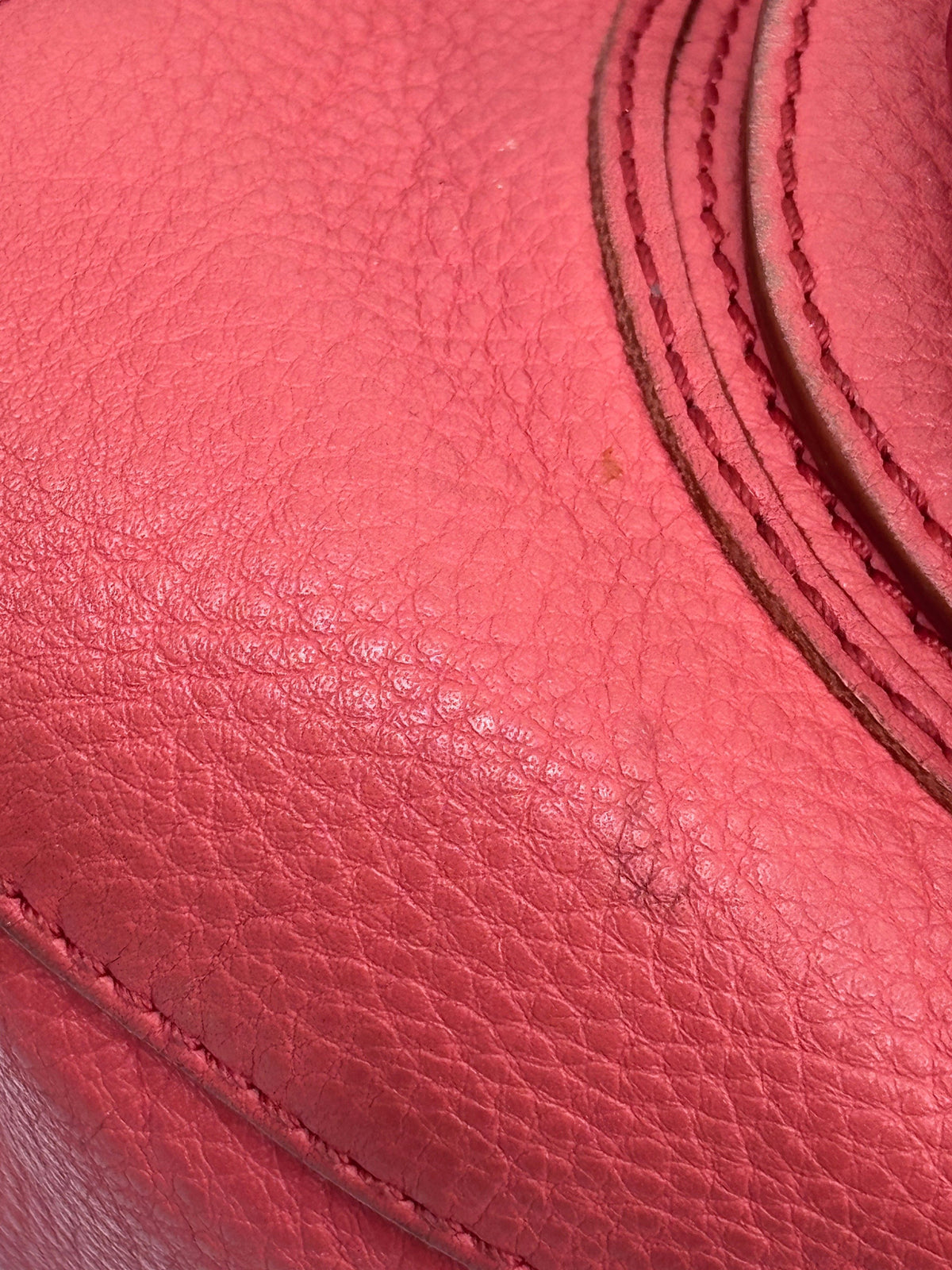 Close-up of coral leather texture and signature curved stitching on a Posh Purse Co. Chloé Marcie medium satchel bag.
