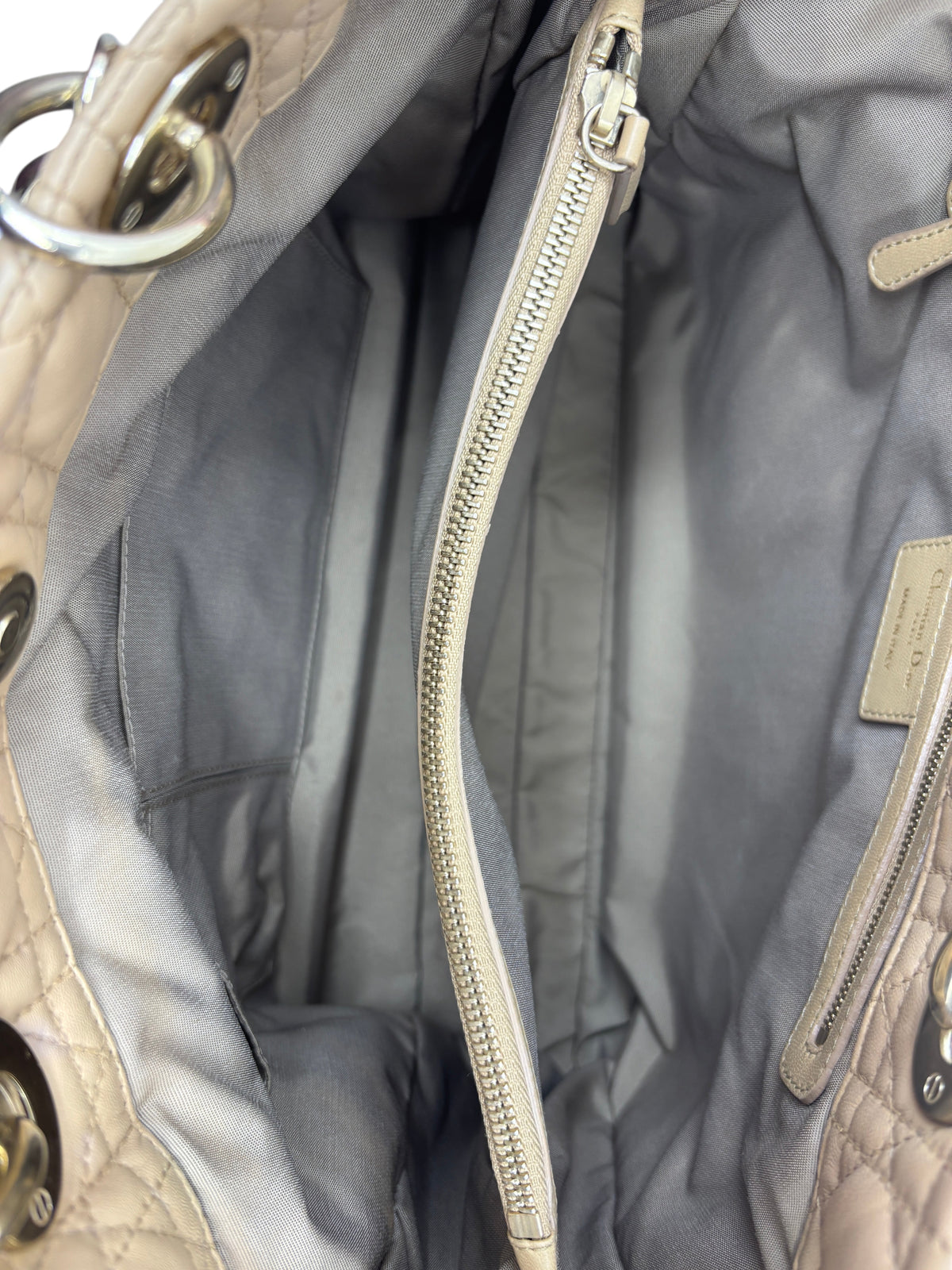 Interior of a preloved beige Posh Purse Co. Dior Cannage tote bag featuring a grey fabric lining and zippered pocket.