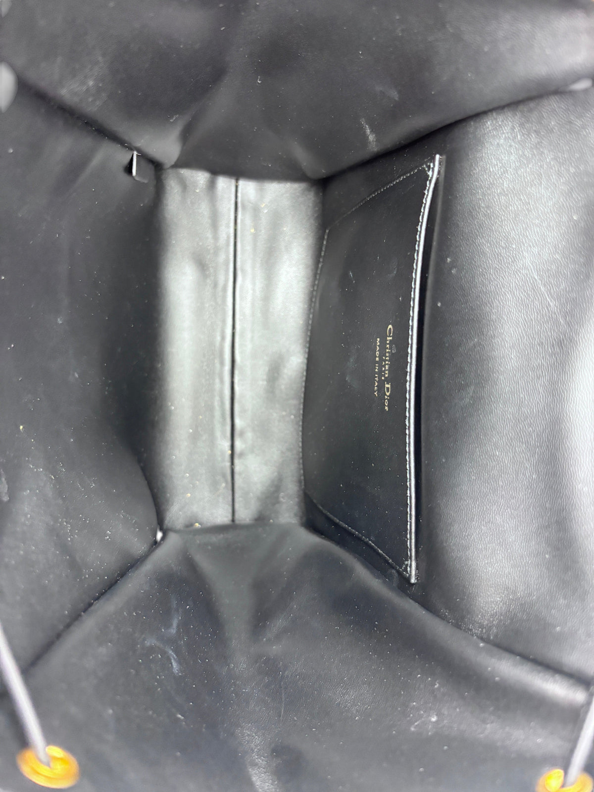 Interior of Posh Purse Co Dior Caro backpack featuring black leather lining and Christian Dior Made in Italy stamp.