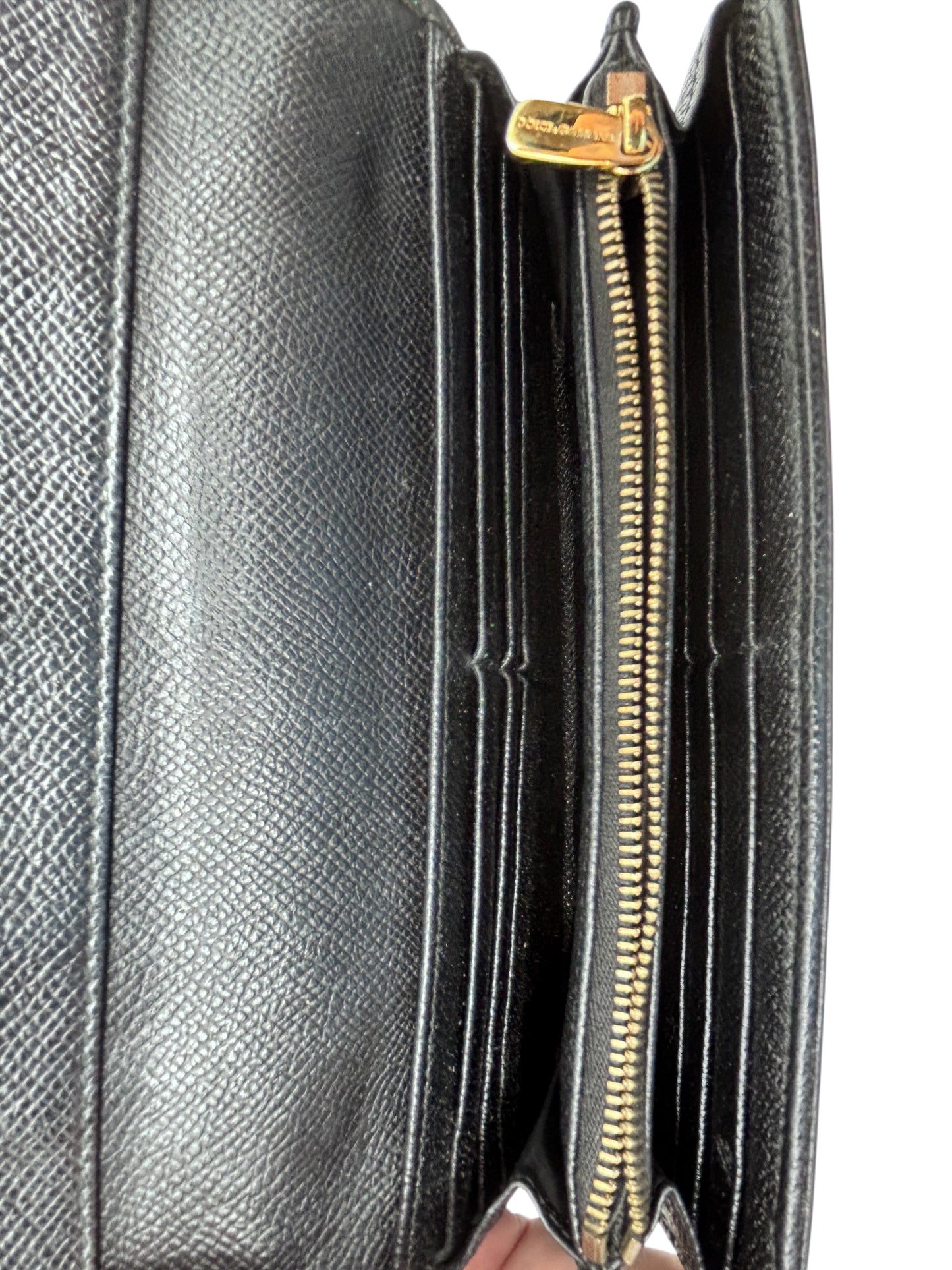 Interior of a black textured leather Posh Purse Co Dolce and Gabbana wallet featuring gold hardware and card slots.