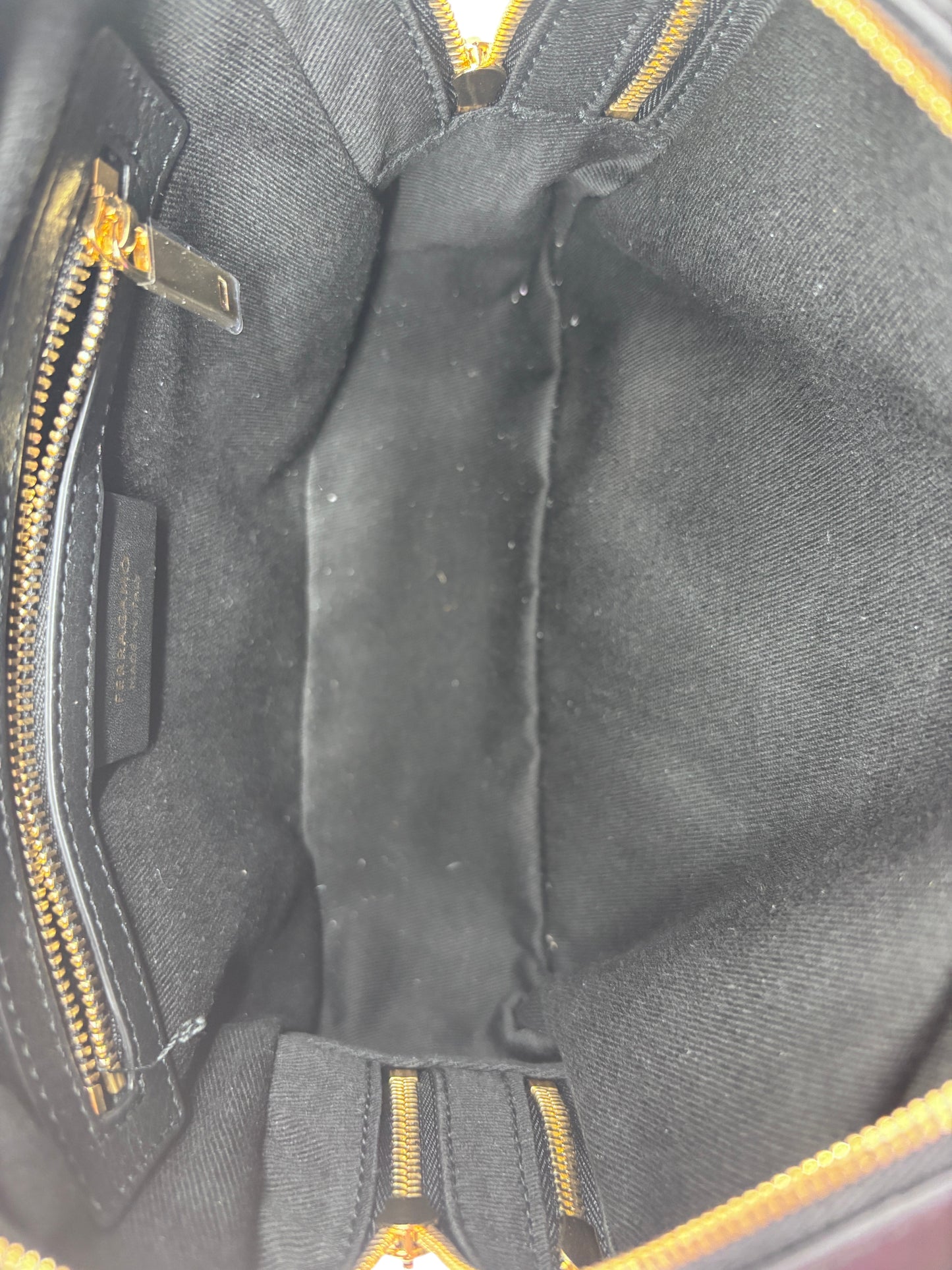 Interior view of Posh Purse Co. black Ferragamo triple zip bag showing clean fabric lining and gold zipper details