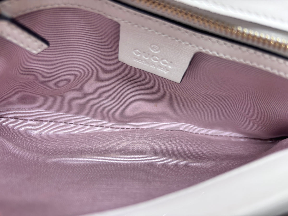 Interior of Posh Purse Co preloved ivory Gucci Arli bag with light pink lining and embossed leather brand logo tag