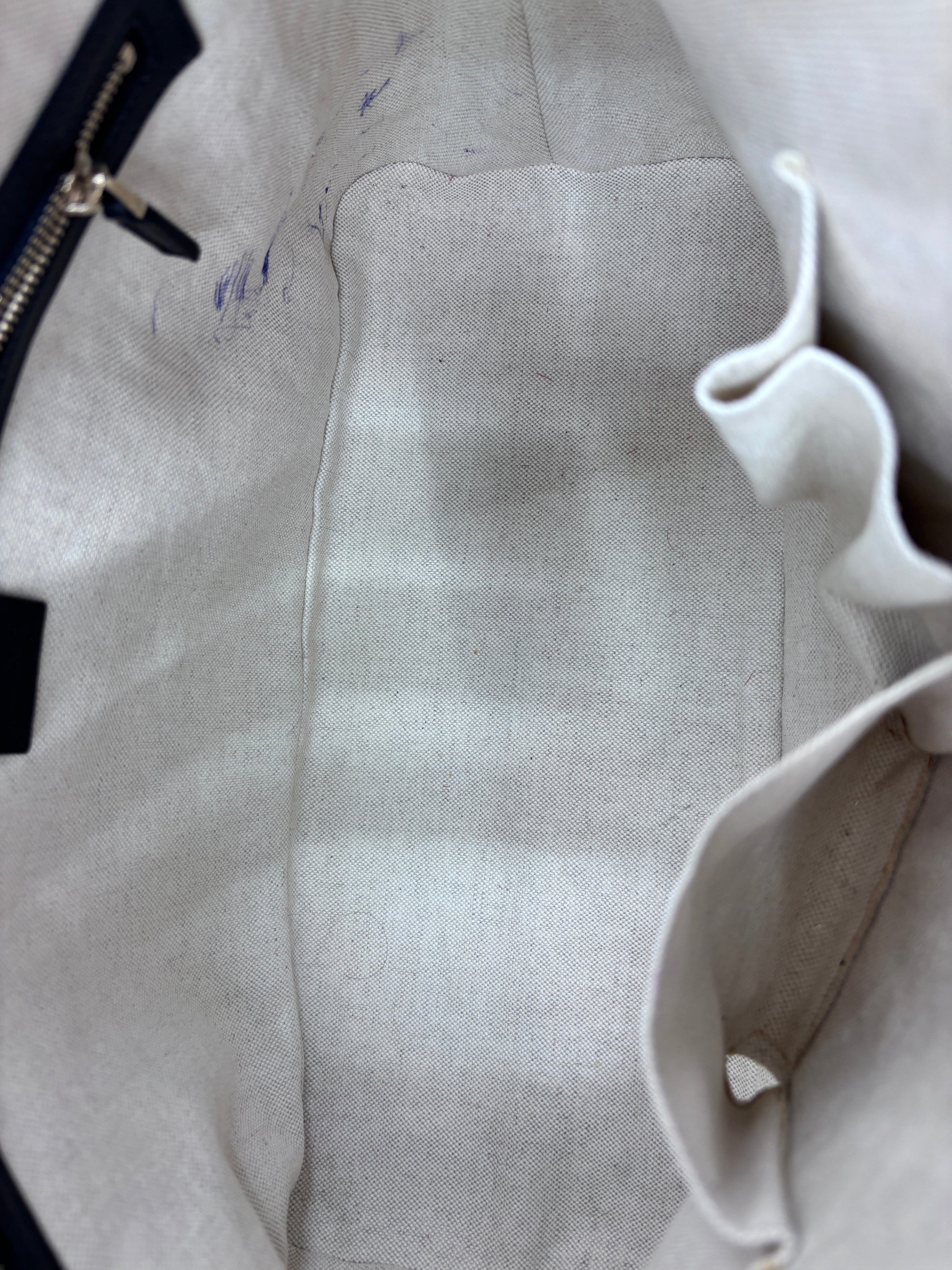 Interior of Posh Purse Co preloved Gucci Micro Guccissima bag featuring light beige fabric lining with pen marks