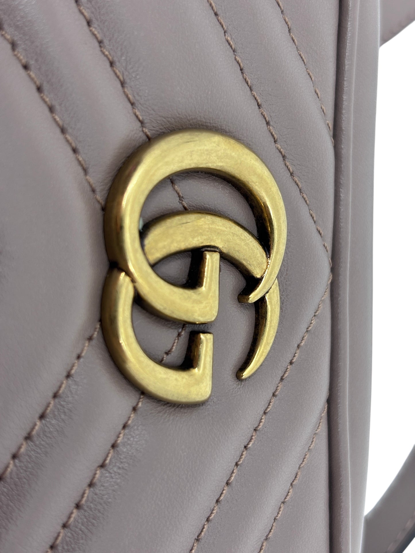 Close-up of the gold GG logo on a beige quilted leather Posh Purse Co. Gucci camera bag