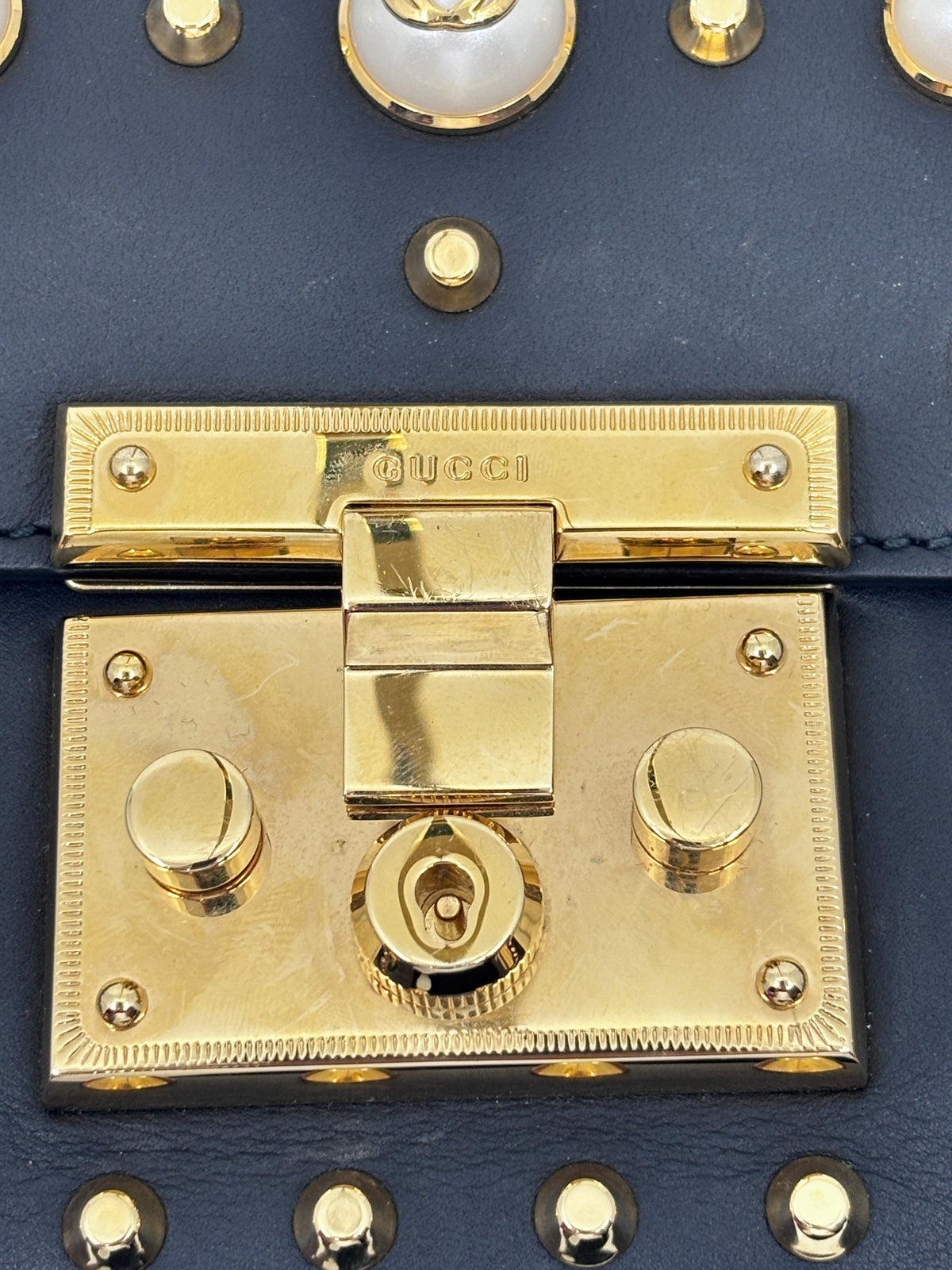 Posh Purse Co black Gucci shoulder bag featuring gold-tone hardware, a signature clasp, and pearl embellishments.