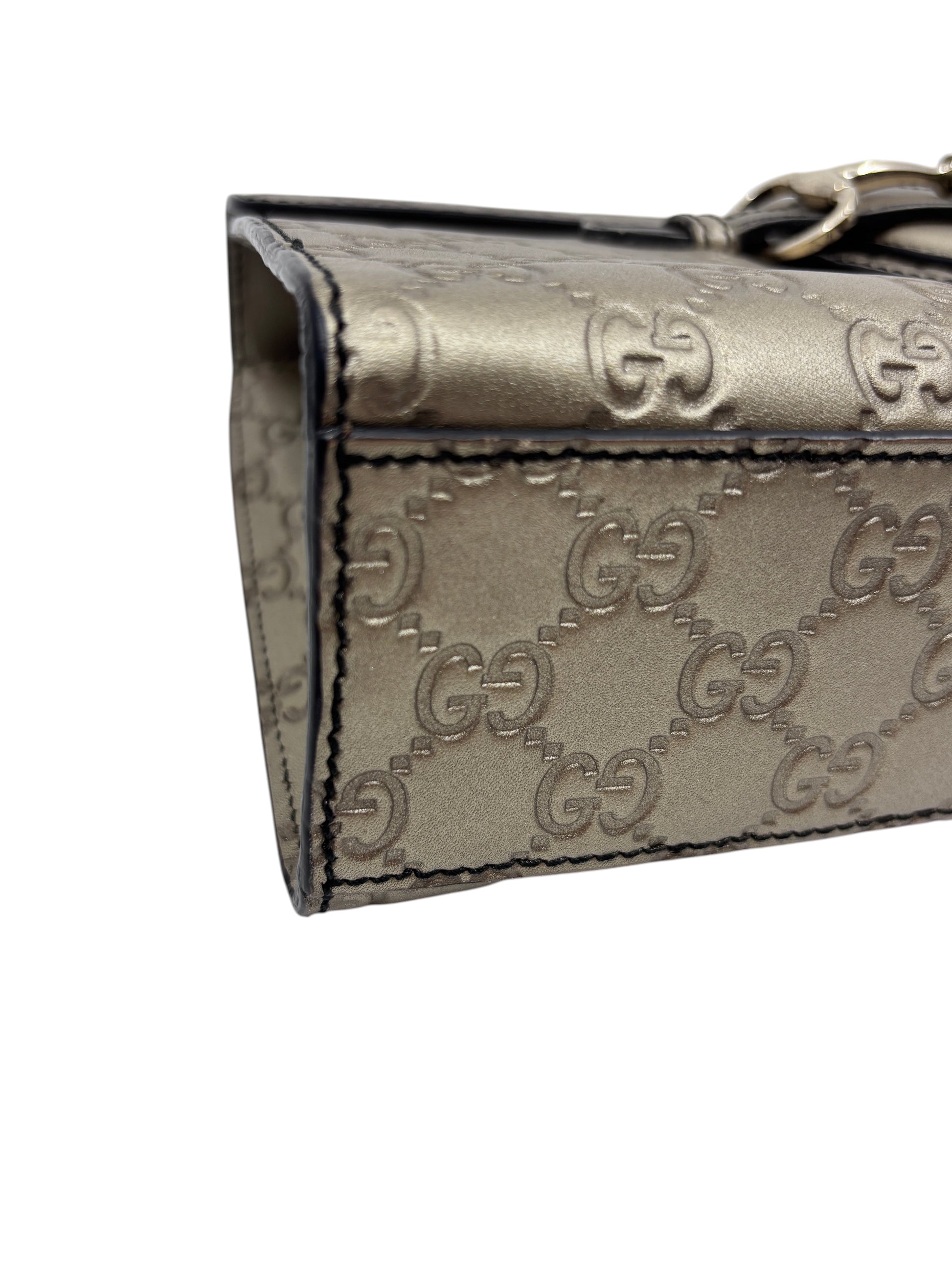 Posh Purse Co. Gucci Guccissima Emily bag side view featuring metallic gold embossed GG leather and black edge trim.