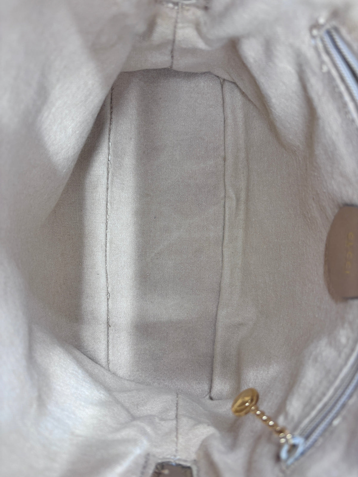 Interior view of a preloved Gucci bamboo handbag with beige fabric lining and a small gold zipper pull by Posh Purse Co