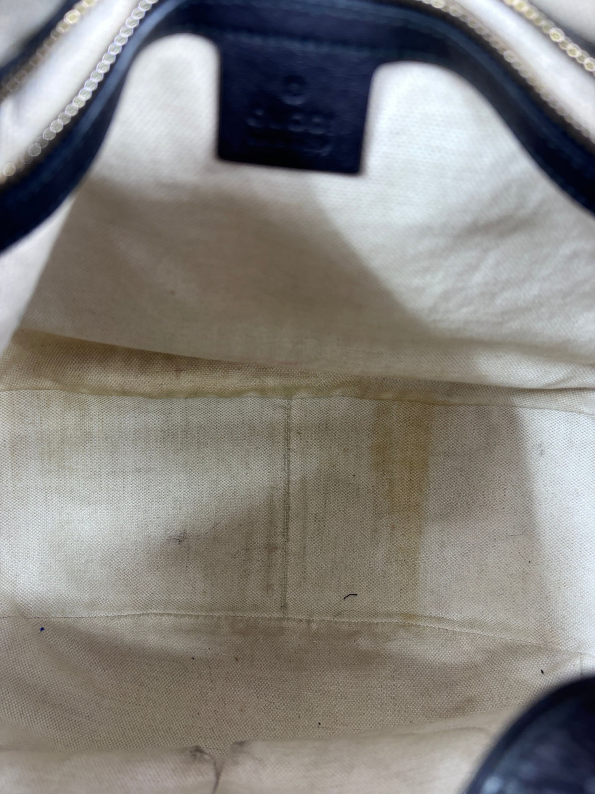Interior view of a preloved Posh Purse Co. Gucci Horsebit 1955 hobo bag showing light fabric lining with staining.
