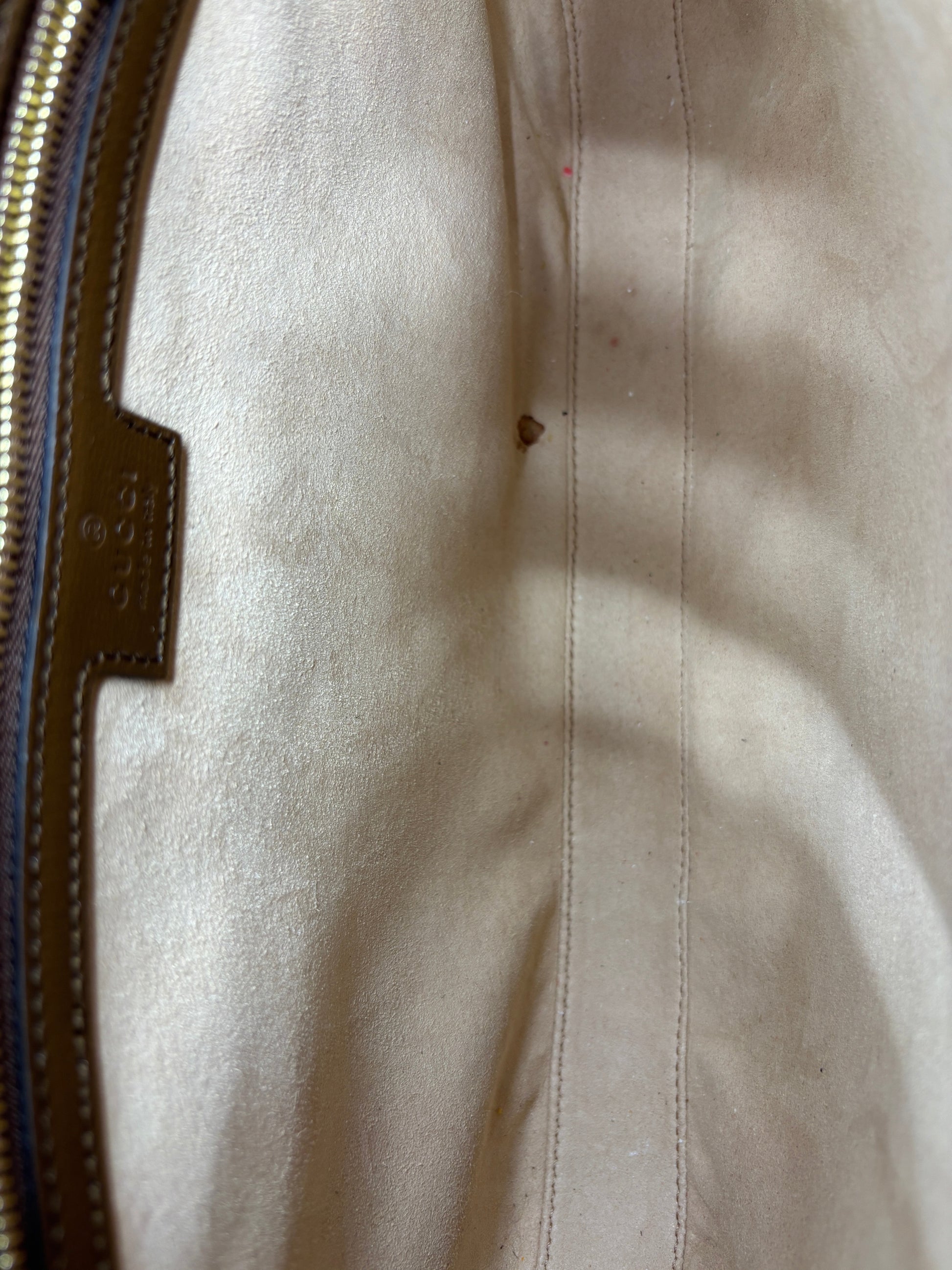 Interior of a preloved Posh Purse Co. Gucci Jackie 1961 shoulder bag featuring beige suede lining and leather tag.