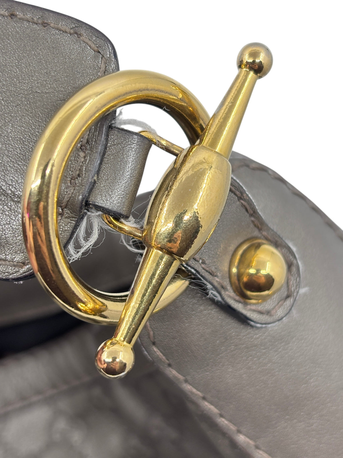 Close-up of the gold-tone toggle hardware on a gray Posh Purse Co. Gucci Jockey shoulder bag
