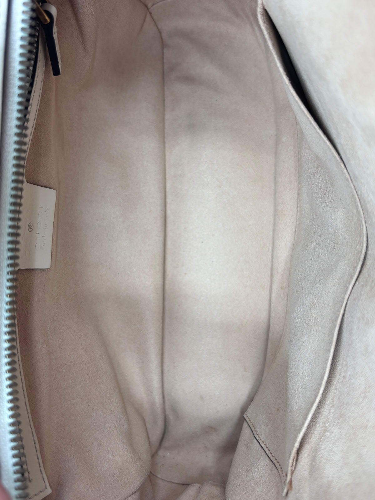 Interior view of a preloved Gucci GG Marmont bag with beige suede lining and Gucci leather brand tag by Posh Purse Co