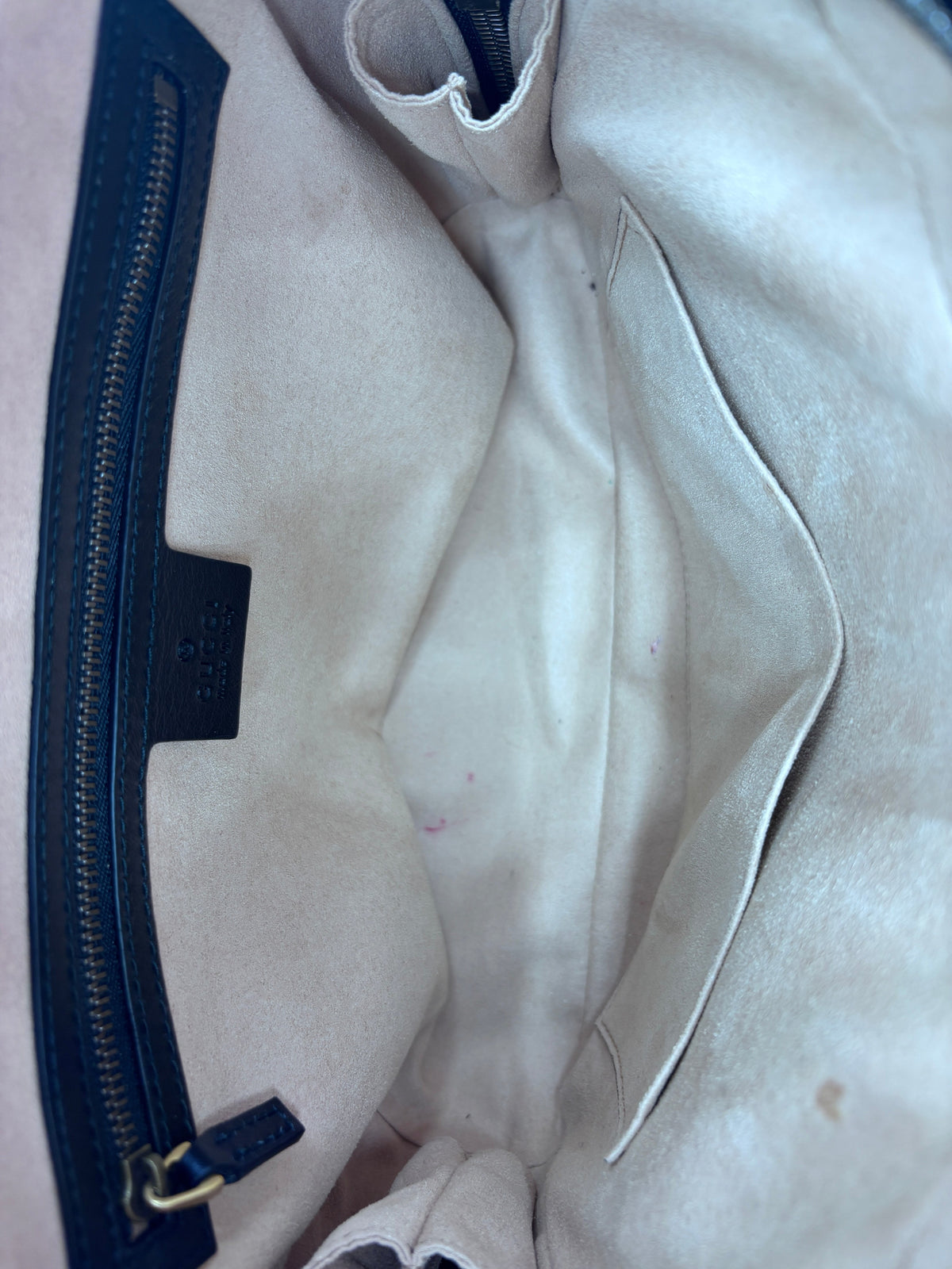 Interior of a preloved Posh Purse Co Gucci Marmont bag featuring a beige suede lining and a black leather zip pocket.