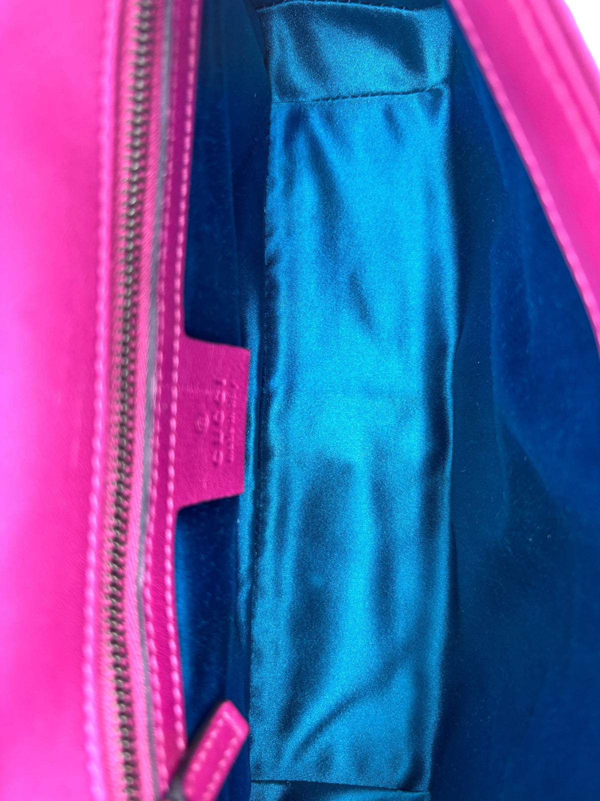 Interior of Posh Purse Co pink Gucci Marmont shoulder bag featuring vibrant blue satin lining and leather logo tag