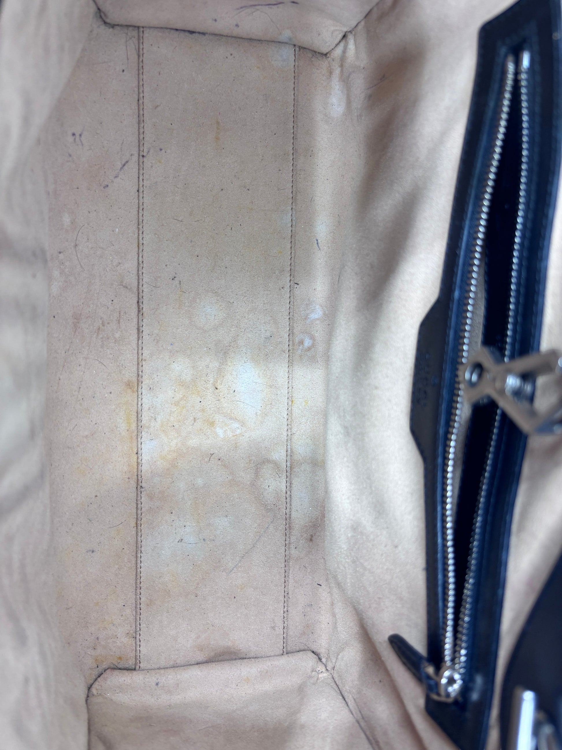 Interior view of Posh Purse Co preloved Gucci Marmont bag showing light beige lining with visible staining