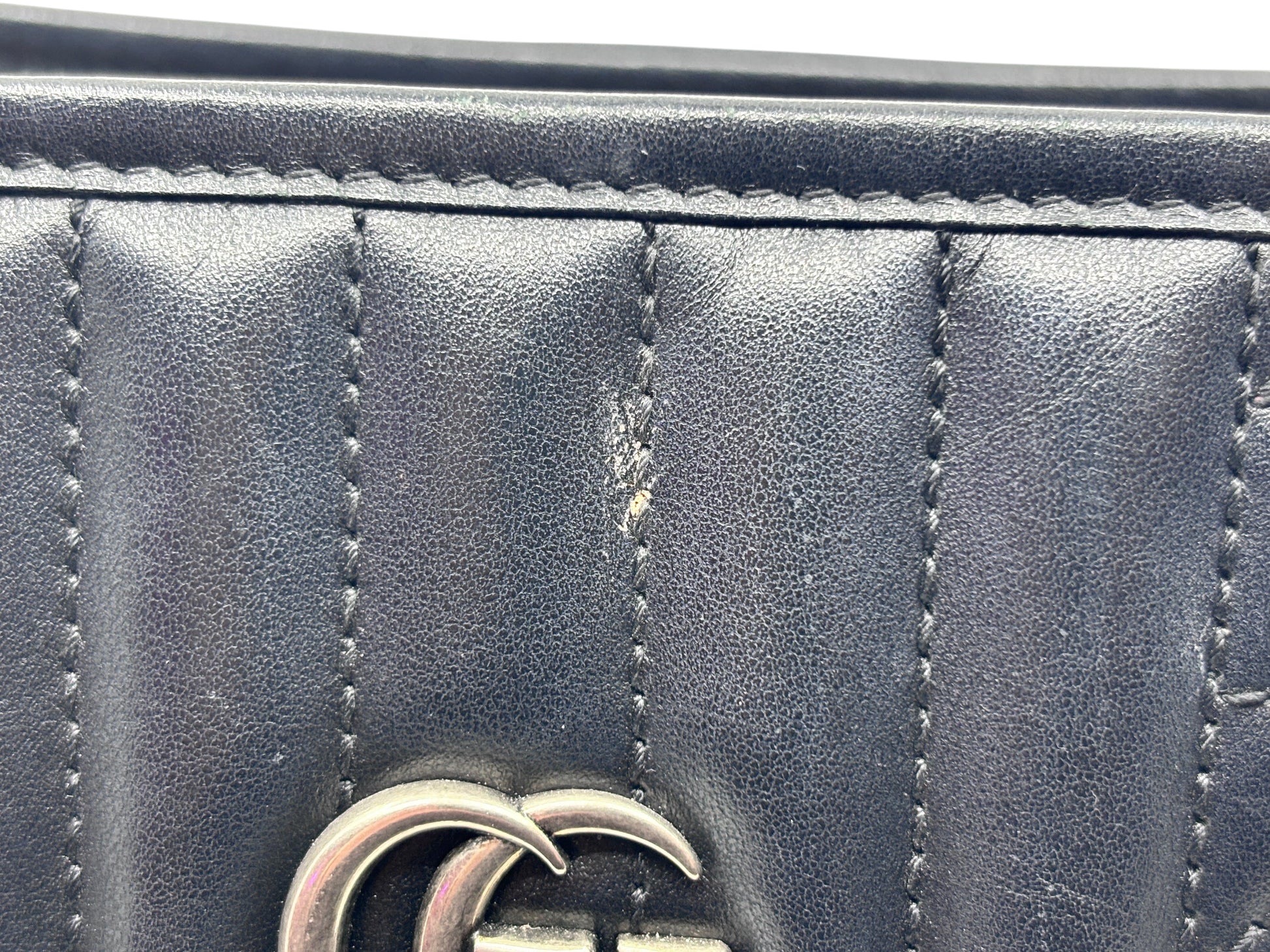 Close-up of Posh Purse Co black matelassé leather Gucci Marmont bag showing surface wear on the chevron quilting