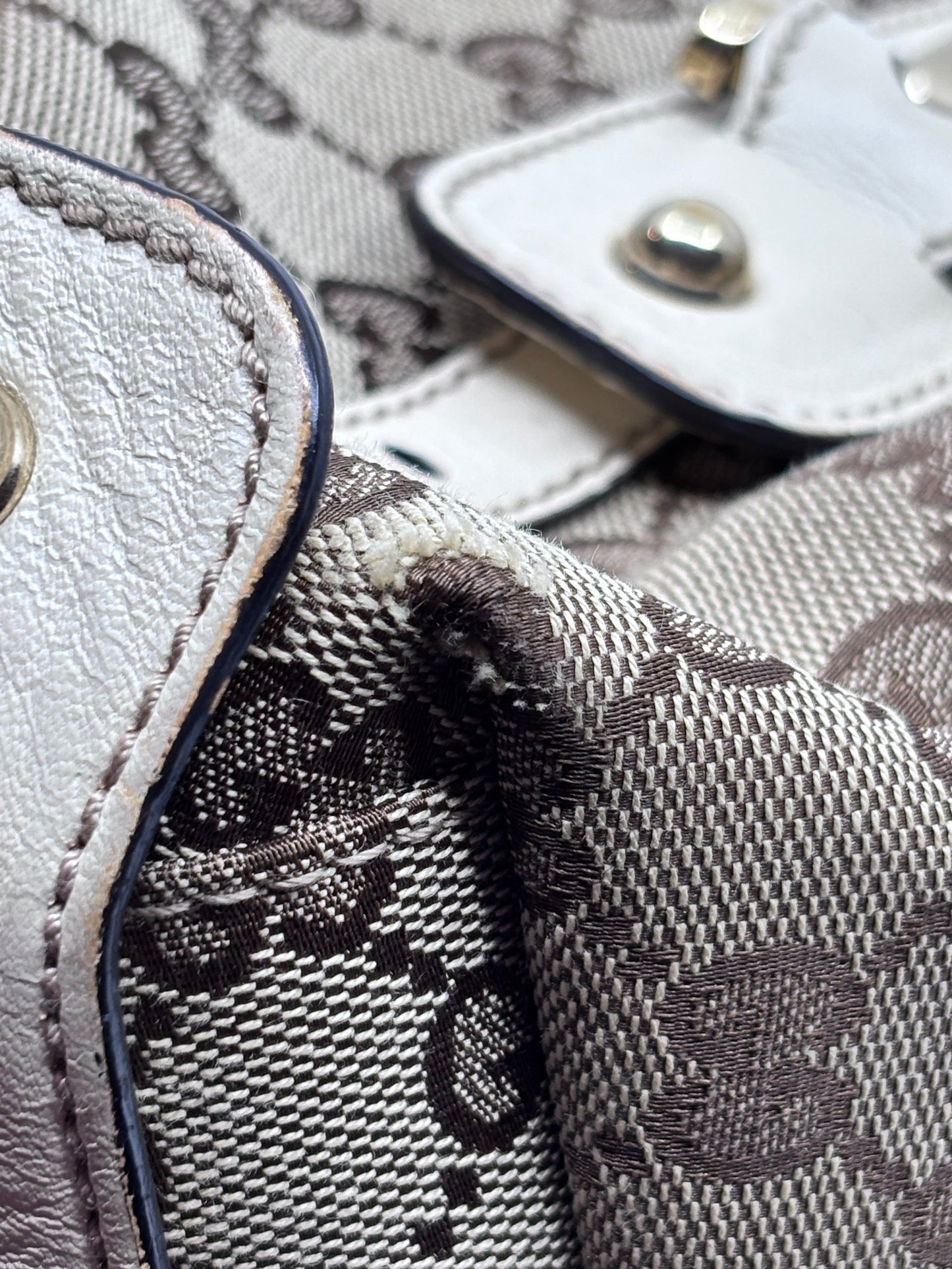 Close-up of Posh Purse Co preloved Gucci Pelham handbag showing monogram canvas, white leather trim, and corner wear.