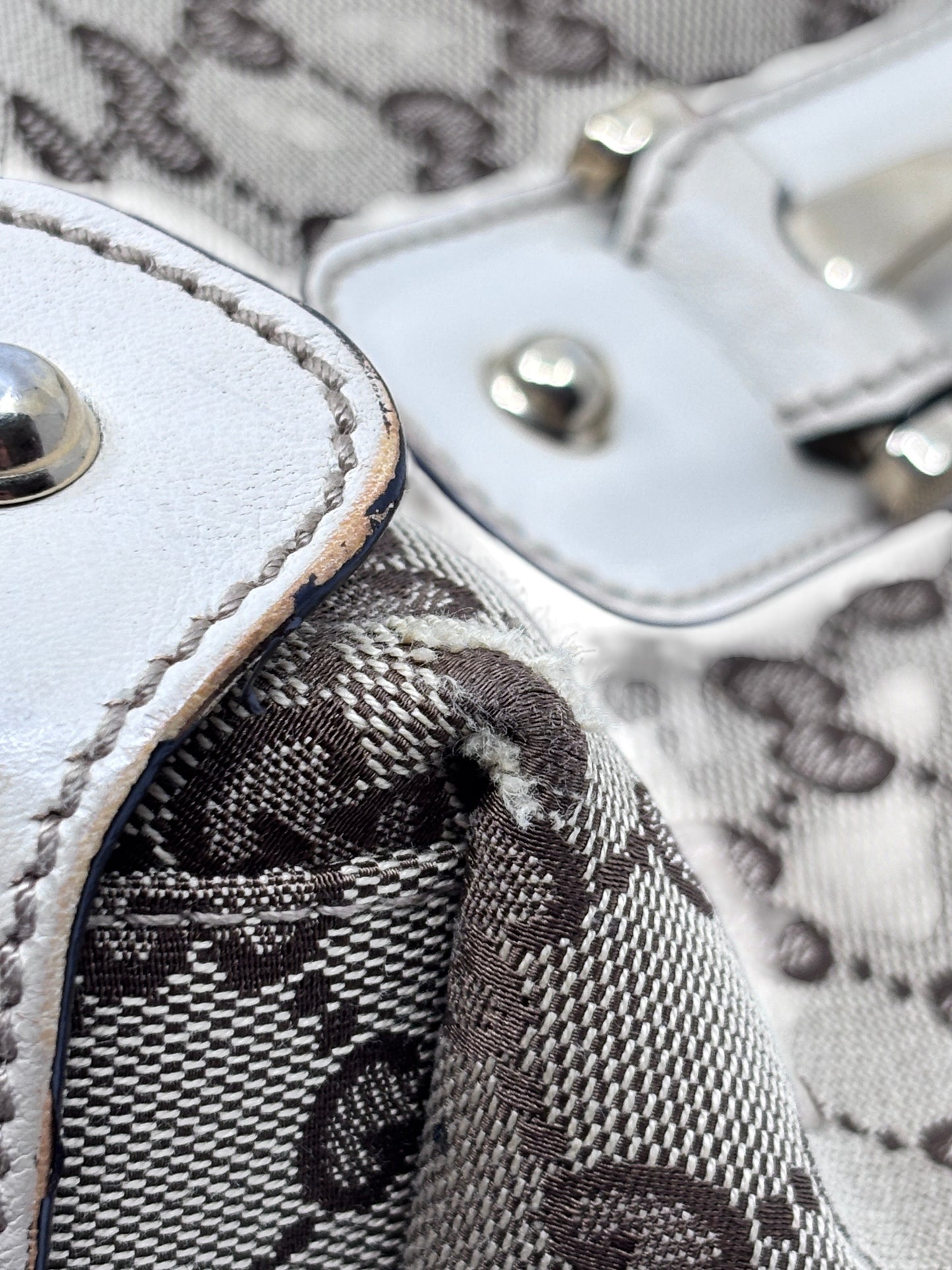 Close-up of Posh Purse Co preloved Gucci Pelham handbag showing canvas monogram wear and white leather trim detail