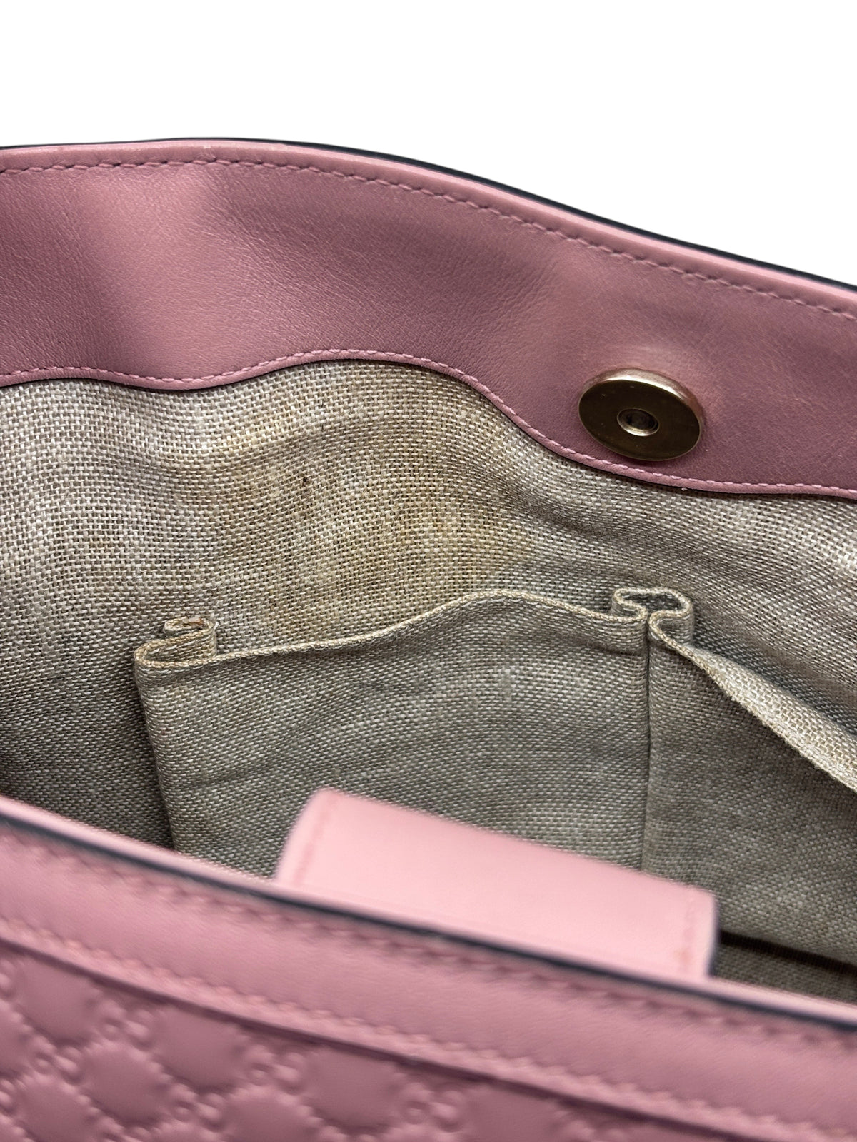 Interior of a pink Posh Purse Co Gucci Micro Guccissima bag showing the beige linen lining and magnetic snap closure