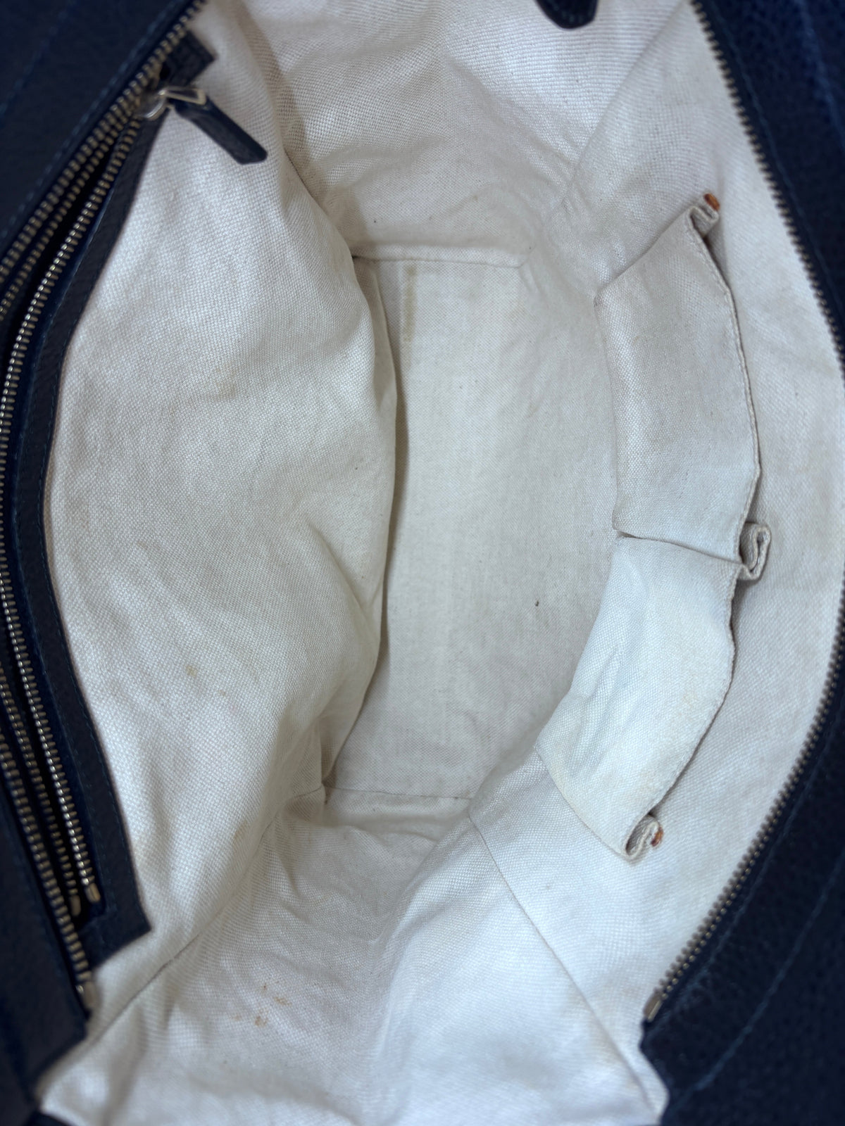 Interior view of the Posh Purse Co navy Gucci Swing Tote showing the spacious cream fabric lining and side pockets.