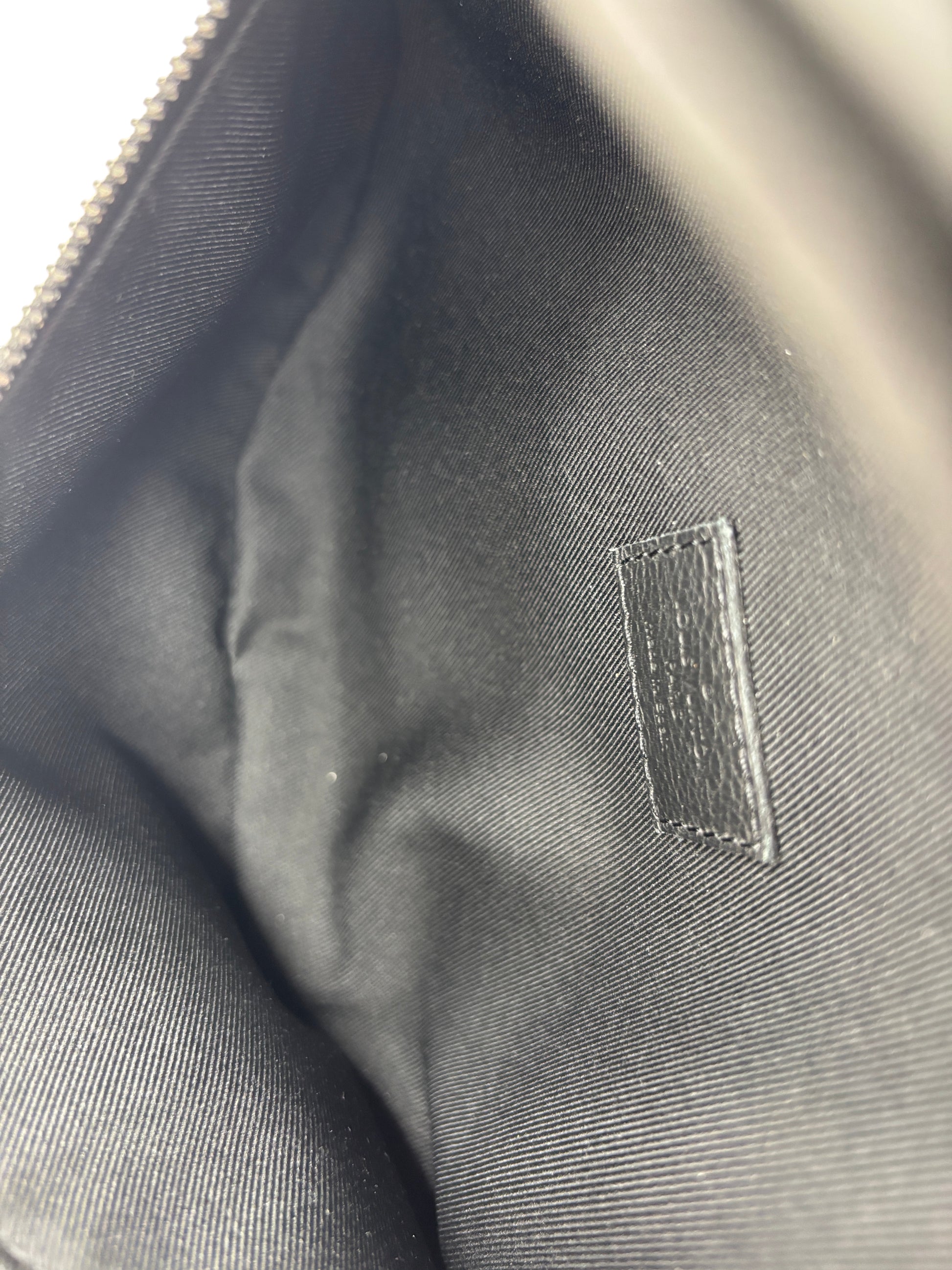 Interior view of a black Louis Vuitton Empreinte Bumbag PM from Posh Purse Co. showing the fabric lining and logo tag.
