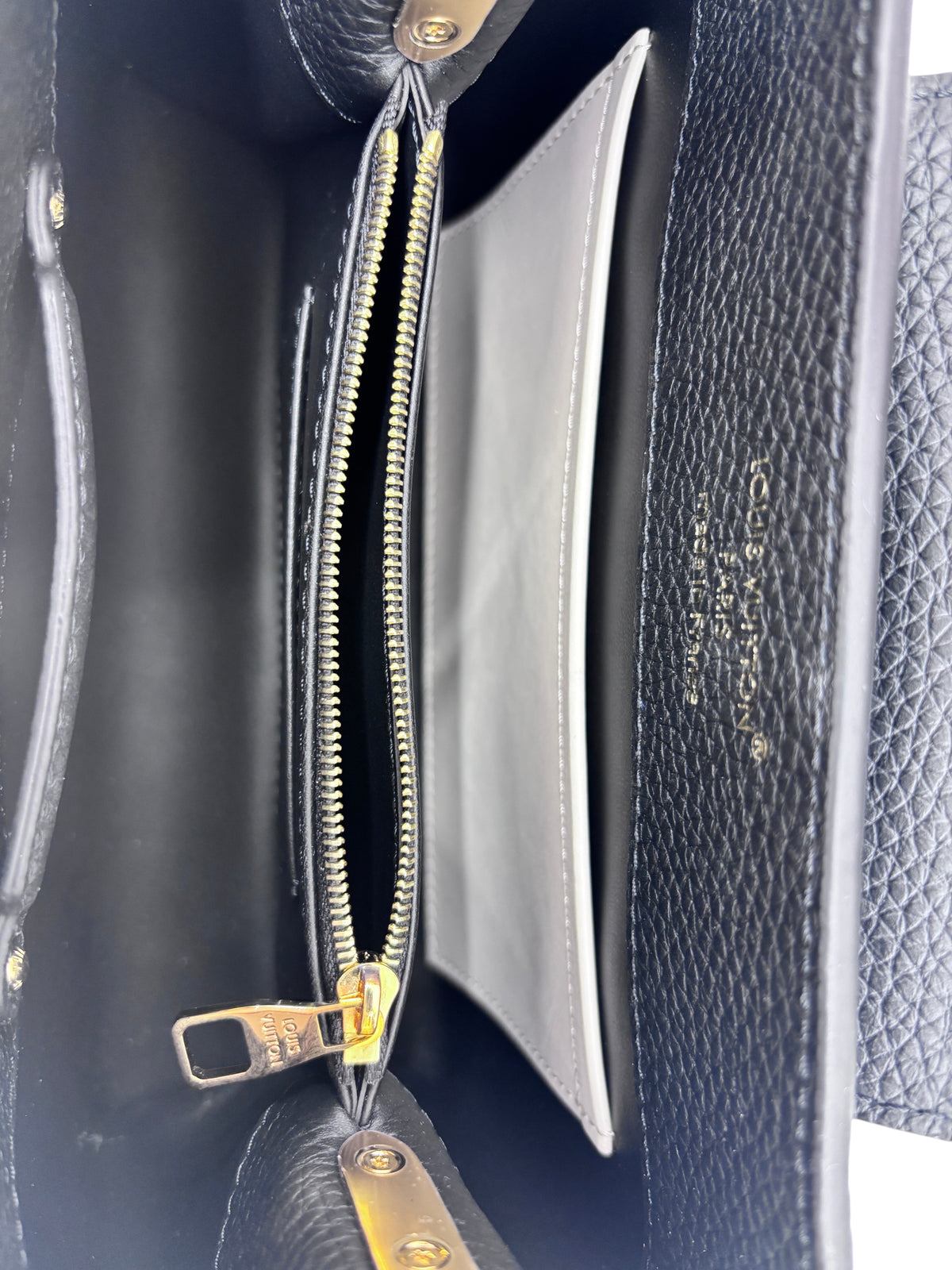 Interior of a black leather Posh Purse Co Louis Vuitton Capucines BB handbag with gold zipper and embossed logo