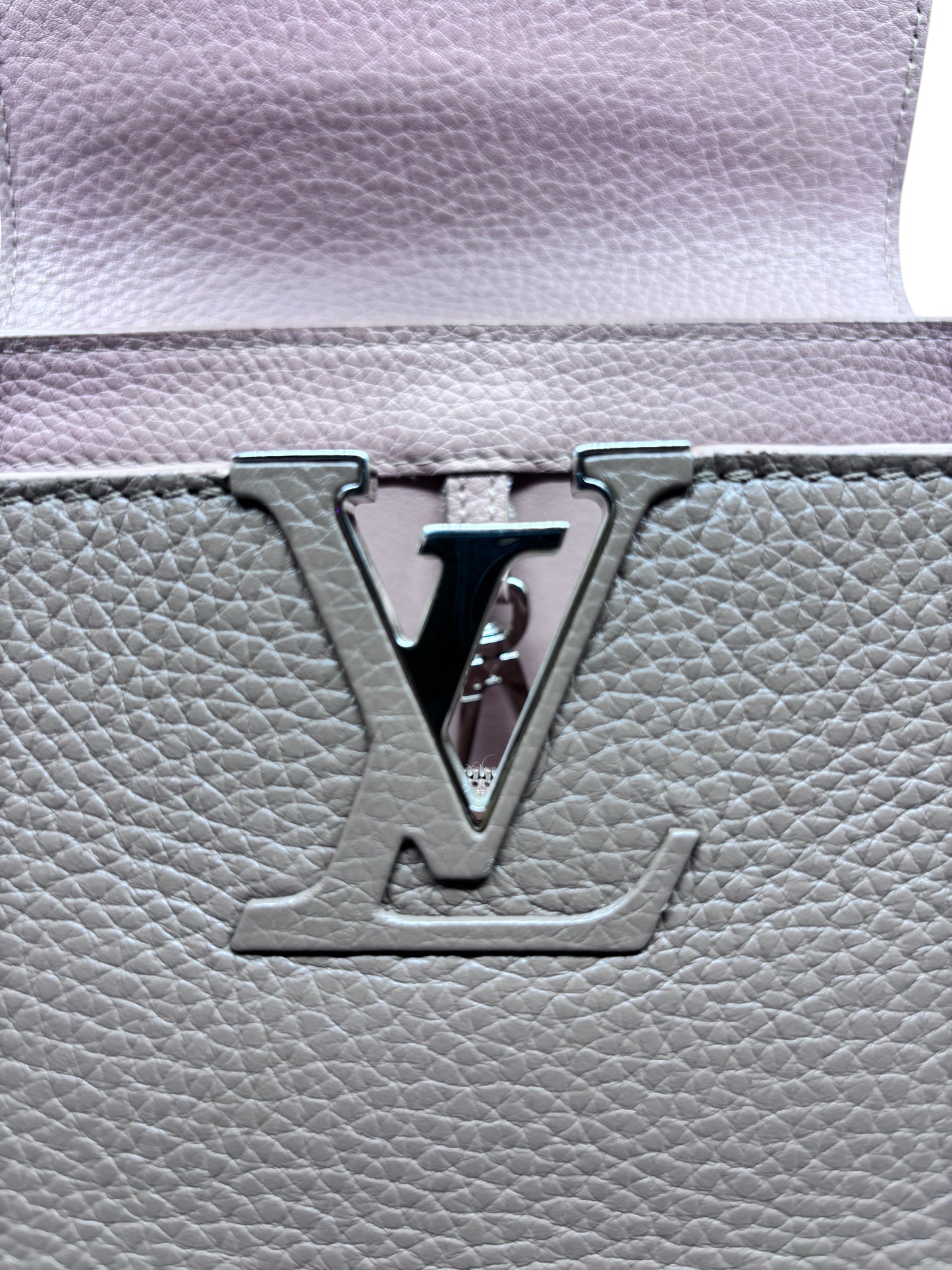 Close-up of the signature LV logo hardware on a beige Posh Purse Co Louis Vuitton Capucines MM leather handbag