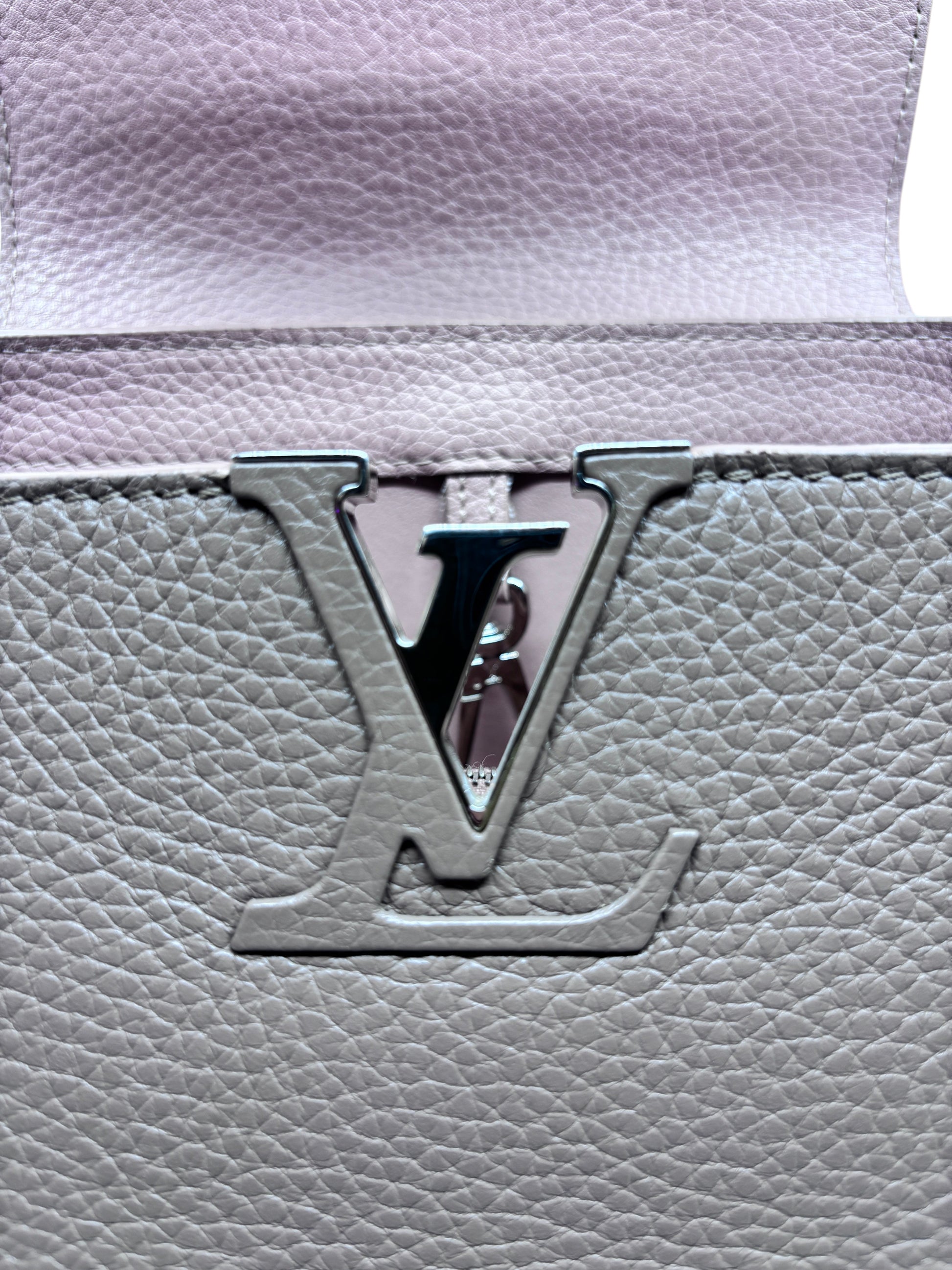 Close-up of the signature LV logo hardware on a beige Posh Purse Co Louis Vuitton Capucines MM leather handbag