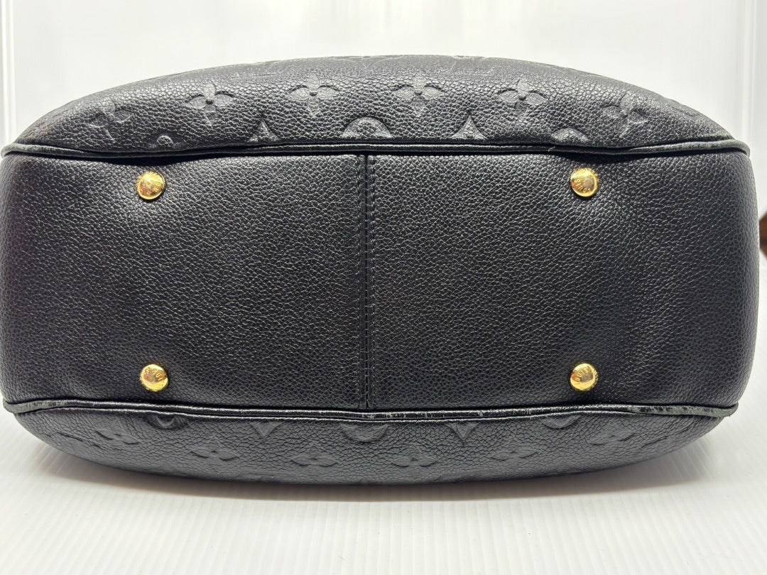 Base of black Louis Vuitton Monogram Empreinte Spontini bag from Posh Purse Co. with gold protective feet.