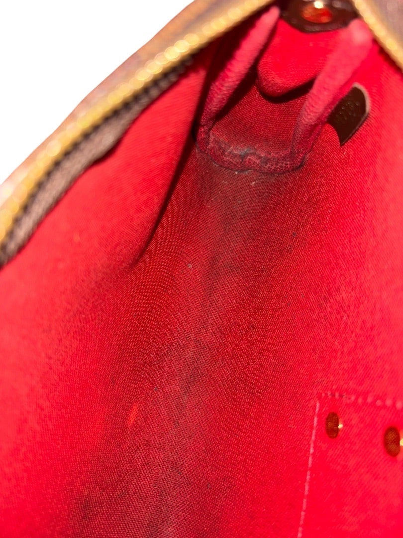 Posh Purse Co. Louis Vuitton Eva Clutch interior with red lining and some visible marks.
