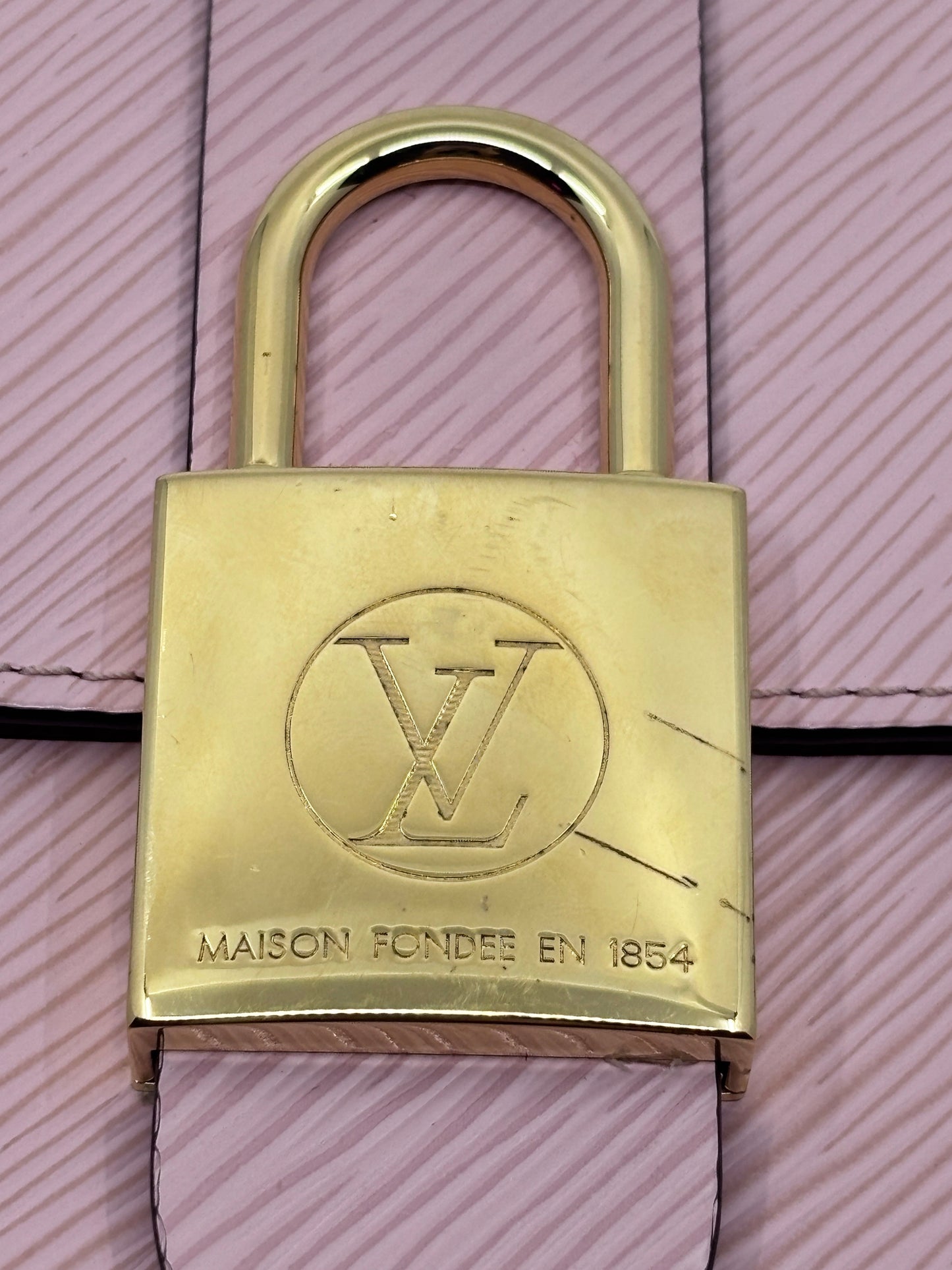 Posh Purse Co. Louis Vuitton Locky handbag featuring a gold-tone signature lock on a textured pink leather background.