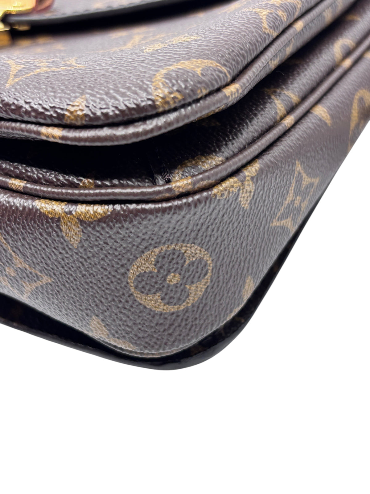 Close-up of Posh Purse Co Louis Vuitton Monogram Pochette Metis coated canvas corner showing signature brown pattern