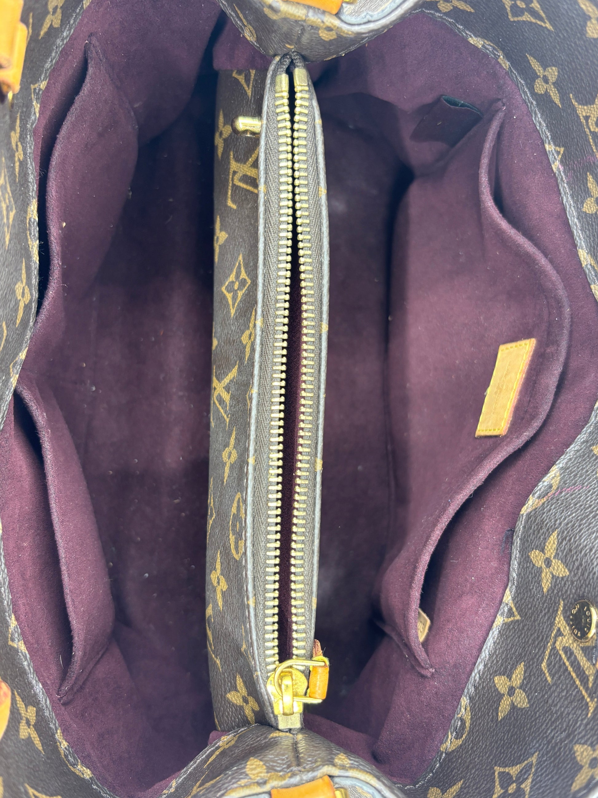 Interior view of Posh Purse Co. preloved Louis Vuitton Montaigne MM bag featuring burgundy lining and central zip pocket