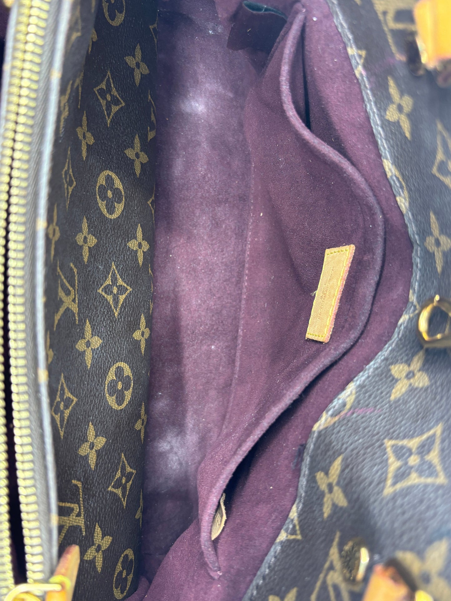 Interior of Posh Purse Co. Louis Vuitton Montaigne MM handbag featuring dark purple lining and monogram canvas pockets.